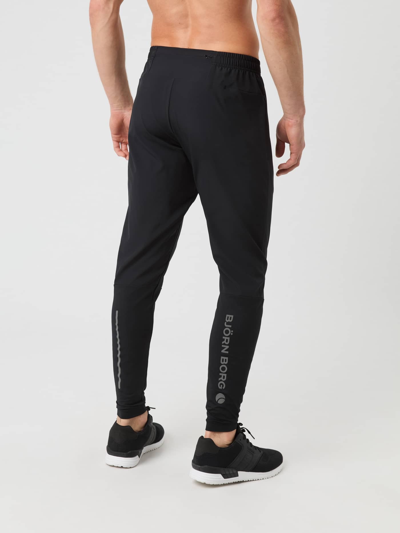 Back view of a man wearing the Borg Running Pants in Black Beauty (Black) with reflective details for running performance. - Image 2