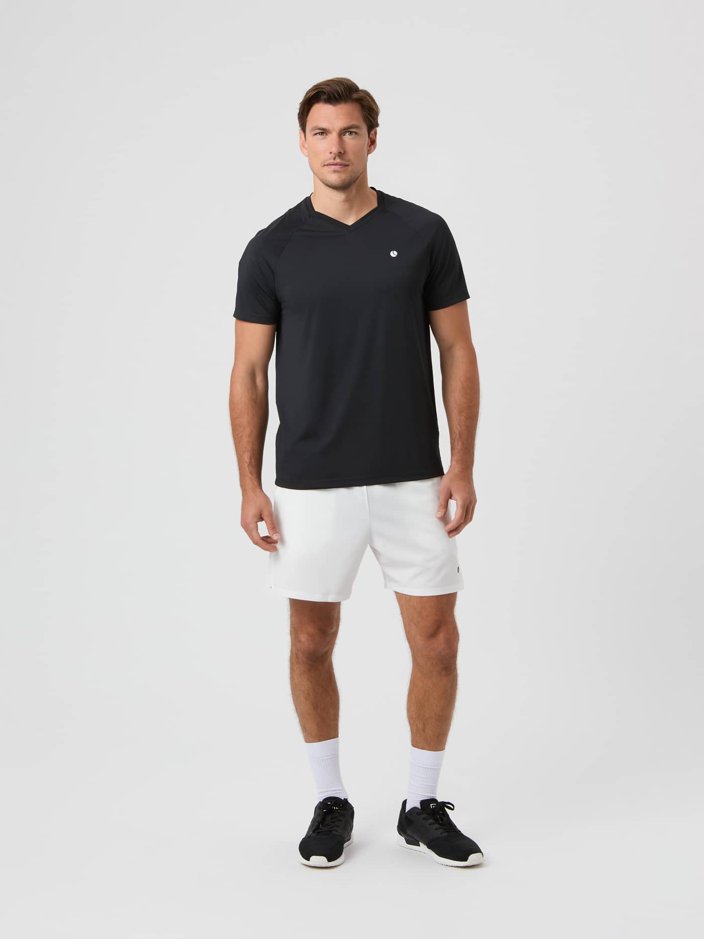 Ace Racquet Shorts 7 inch i Brilliant White (Hvid) set i helfigur på en model stylet med en sort t-shirt til tennis. - Image 5
