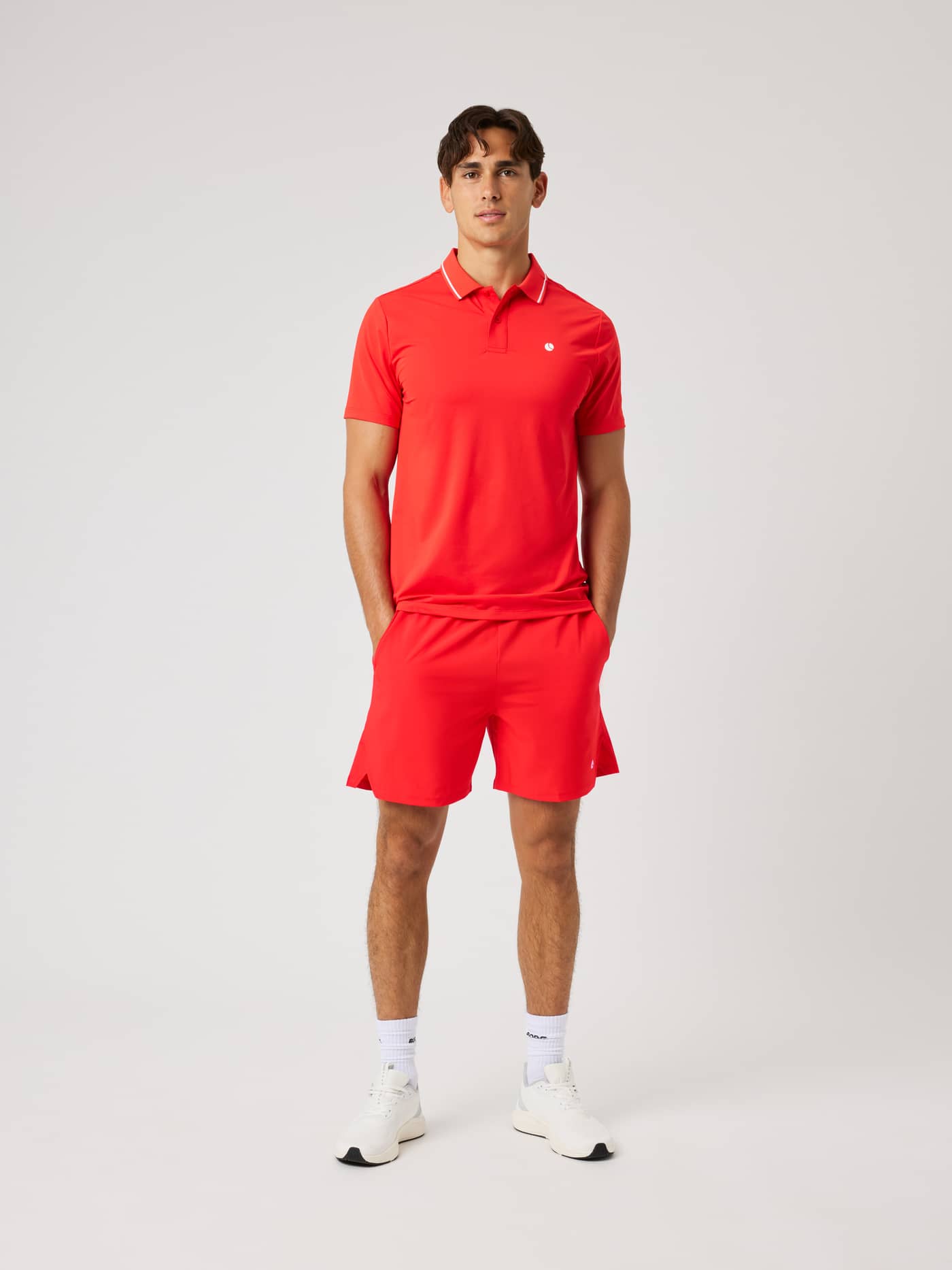 Full-body front view of a model in Flame Scarlet (Red) Ace Racquet Shorts 7 Inch with a white logo for tennis. - Image 3