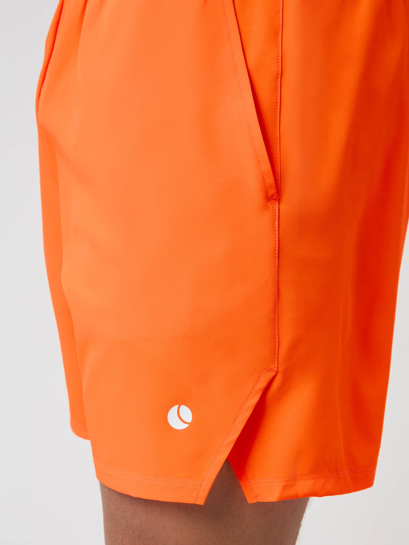 Detail shot of the Björn Borg Ace Racquet Shorts in Shocking Orange, showing the side pocket, slit hem, and logo. - Image 4