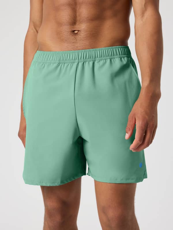 Vue de face d'un homme portant le Ace Racquet Shorts 7 Inch en Malachite Green (Vert) pour le tennis avec logo bleu.