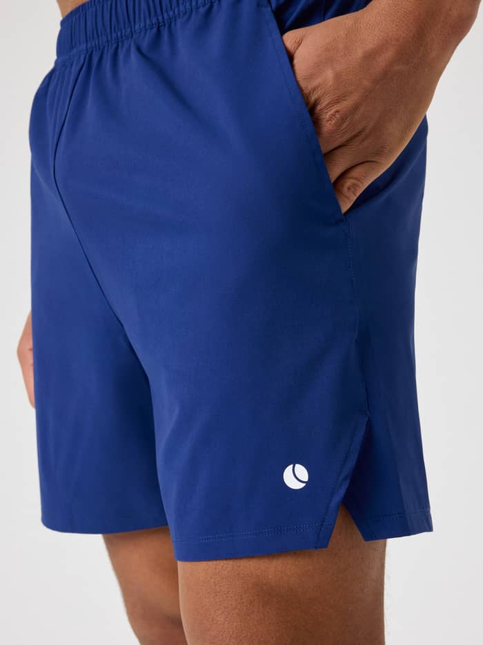 Ace Racquet Shorts 7 Inch i Blue Depths (Blå) set fra siden med sidelomme og hvidt tennisbold-logo til tennis. - Image 4