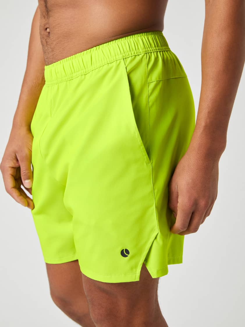 Side profile of a man wearing Björn Borg Ace Racquet Shorts in Acid Lime, showing the side pocket and slit hem. - Image 4