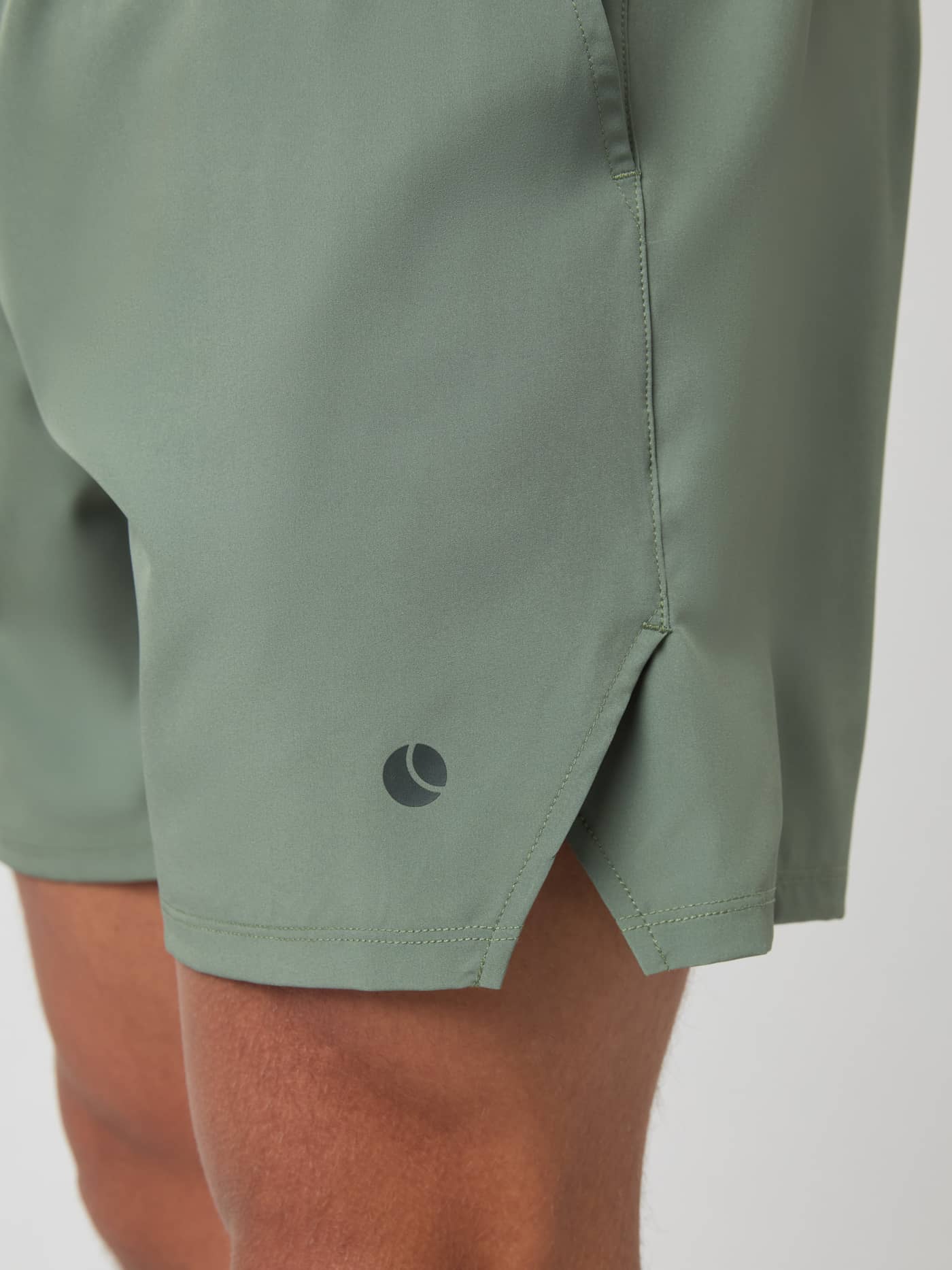 Close-up detail shot of the Björn Borg Ace Racquet Shorts in Agave Green, focusing on the side slit and tennis ball logo. - Image 4
