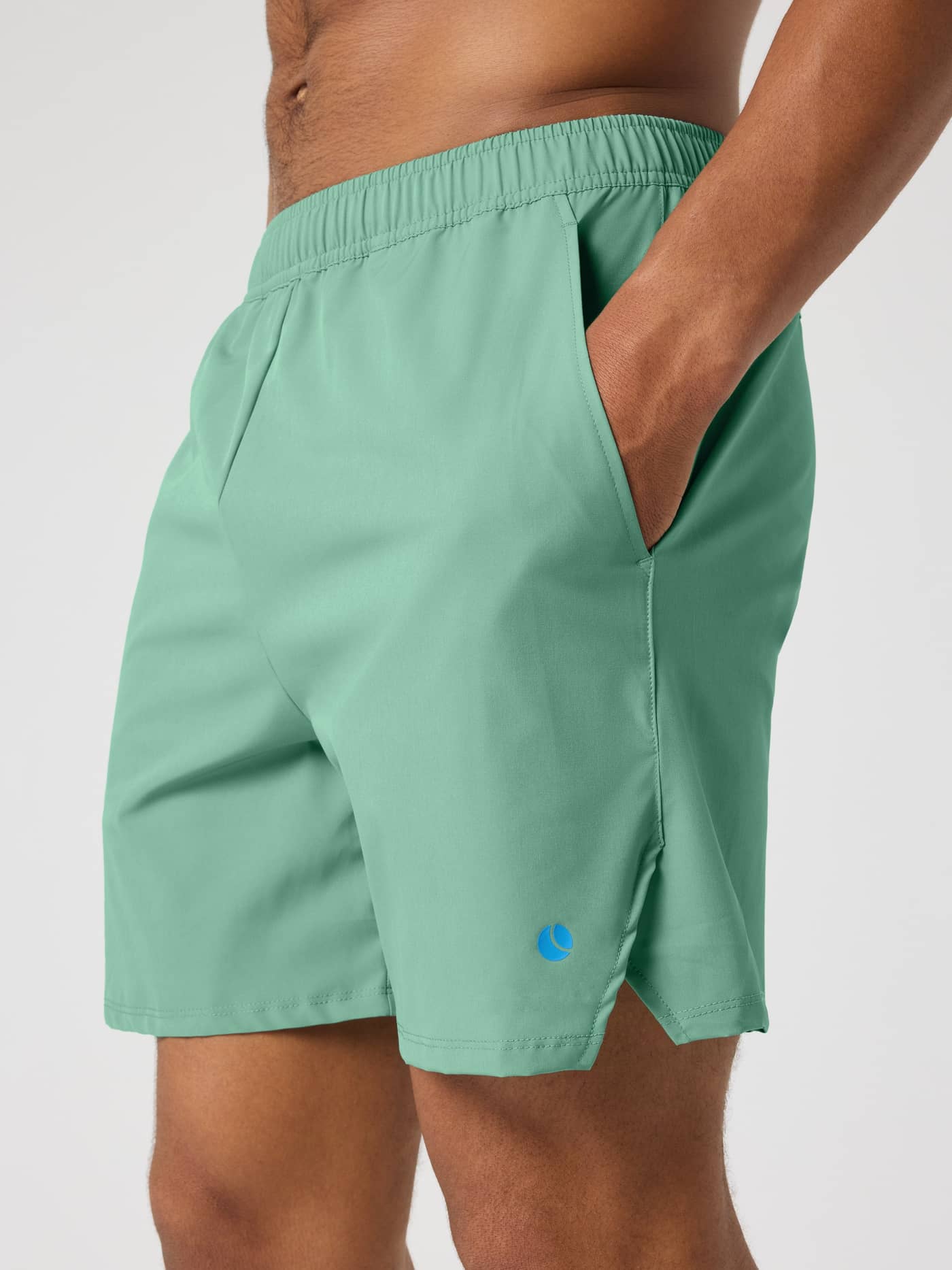 Vista lateral de los Ace Racquet Shorts 7 Inch en Malachite Green (Verde) con logo de pelota de tenis azul y gran estilo. - Image 4