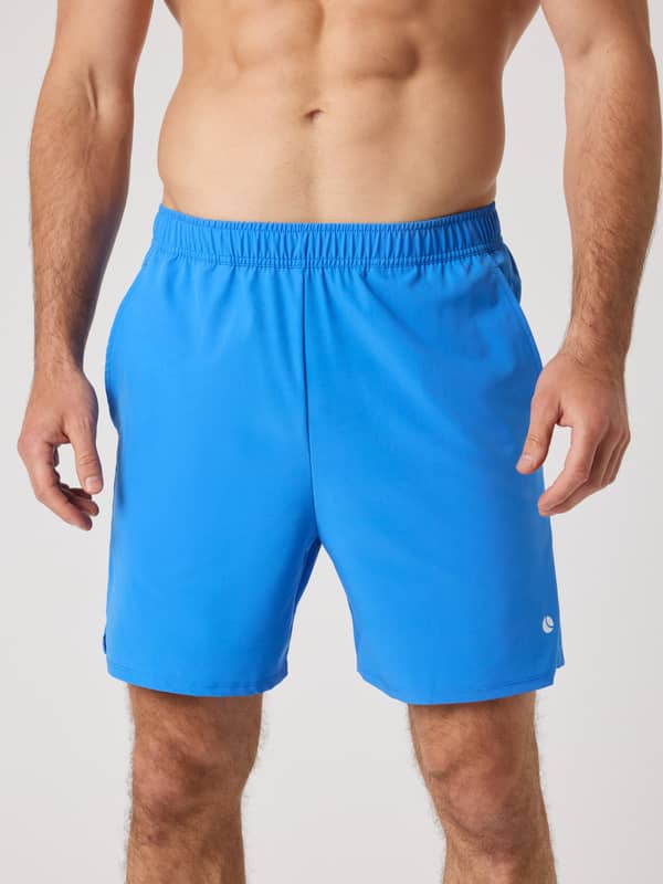 Vue de face d'un homme en Ace Racquet Shorts 7 Inch en Palace Blue (Bleu), short de tennis extensible avec logo blanc.