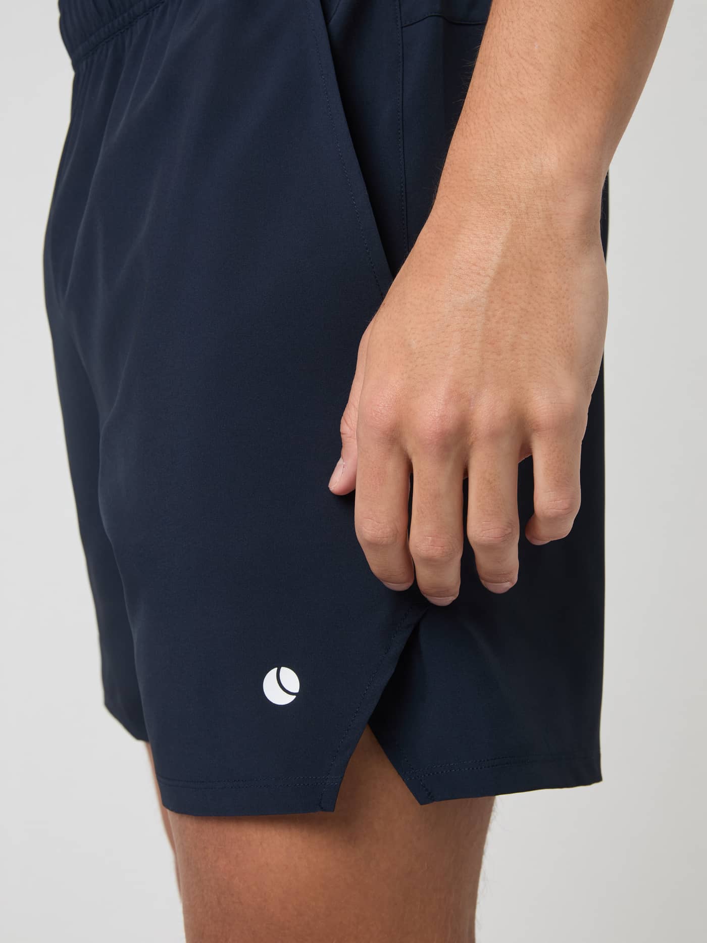 Seitenansicht der Ace Racquet Shorts 7 inch in Night sky (Marineblau) für Tennis mit Schlitz, Tasche und weißem Logo. - Image 4