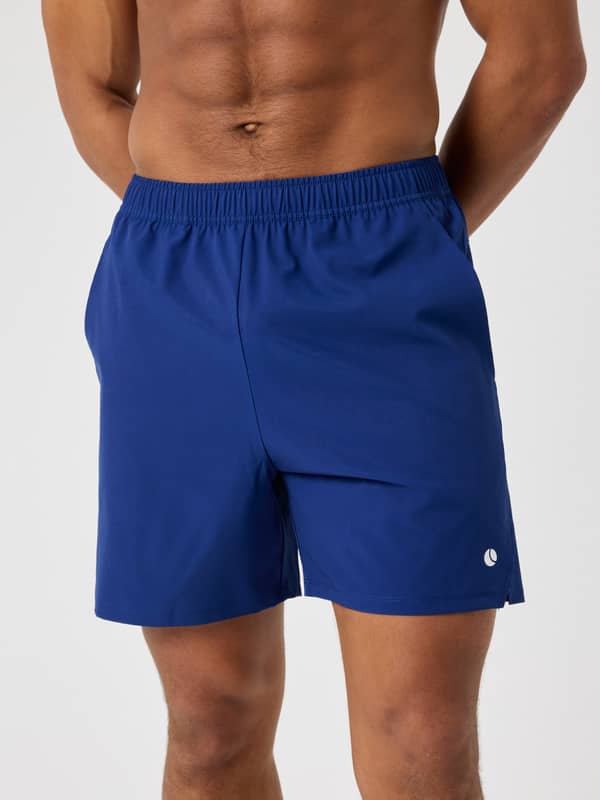 Front view of a man wearing the Björn Borg Ace Racquet Shorts 7 Inch in Blue Depths (Blue) with a white tennis ball logo.