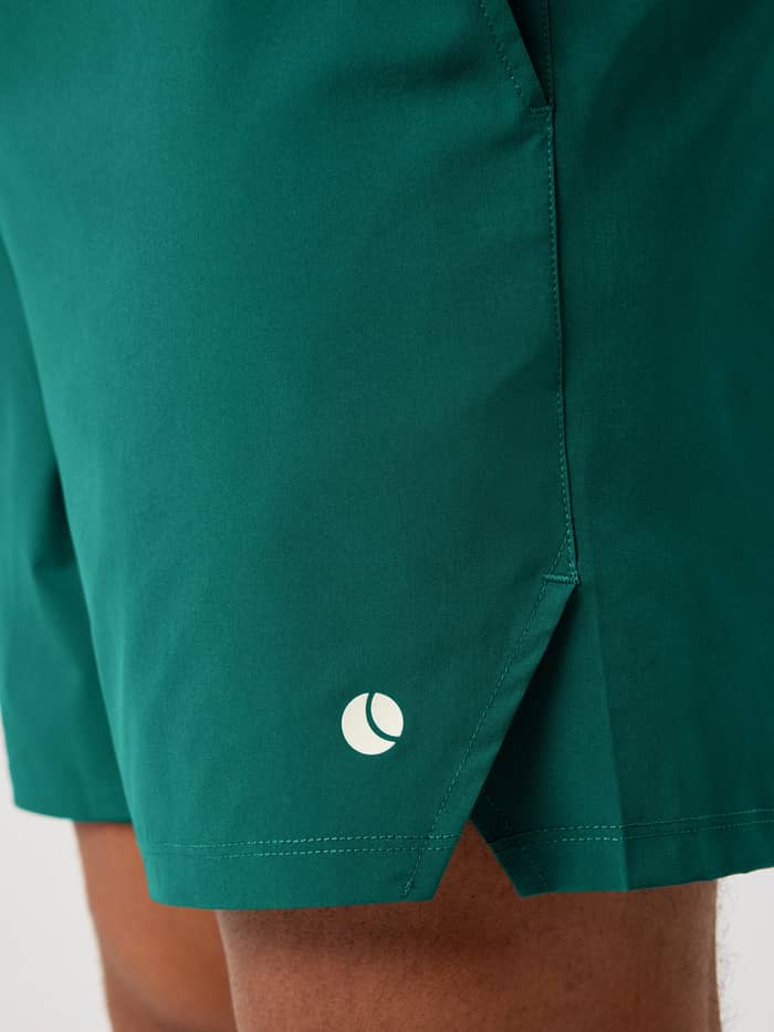Ace Racquet Shorts 7 Inch i Posy Green (Grøn) set i nærbillede fra siden med slids og hvidt tennisbold-logo til tennis. - Image 4