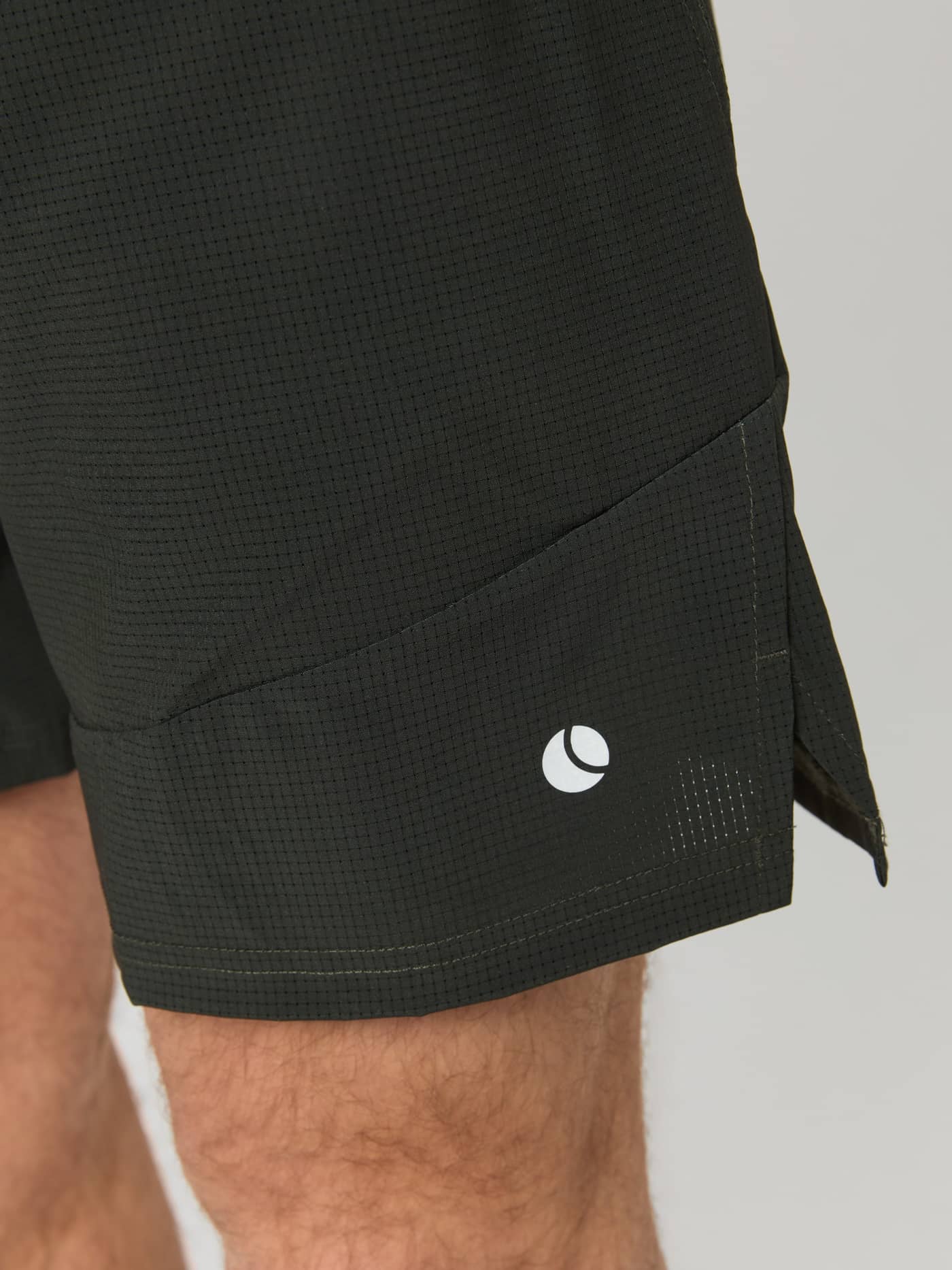 Side detail of the textured Ace Pro Shorts 7 Inch in Peat (Green) for tennis, featuring a functional slit and white logo. - Image 4
