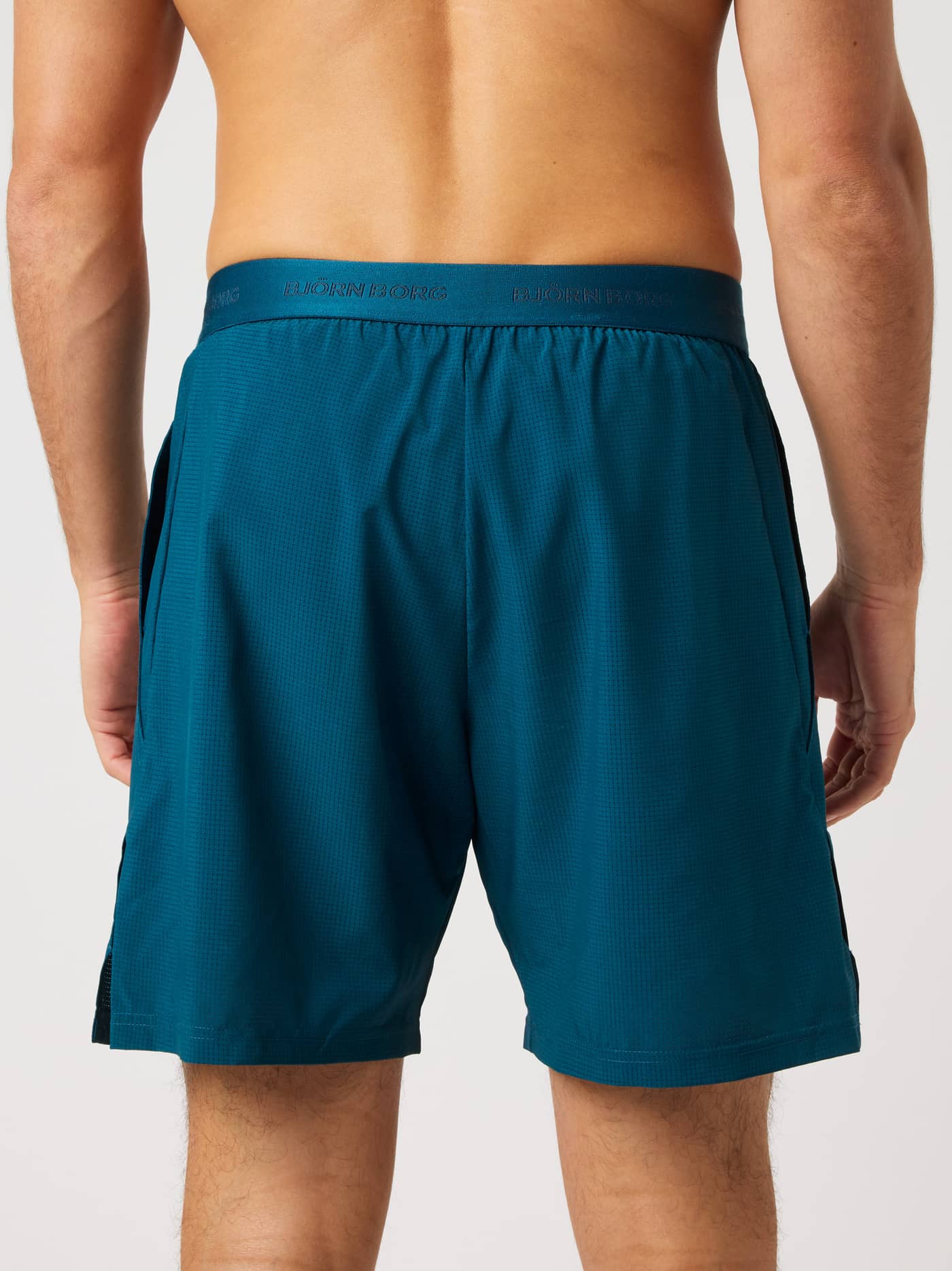 Back view of a model in Ace Pro Shorts 7 Inch in Reflecting Pond (Green) with a branded waistband for tennis. - Image 2