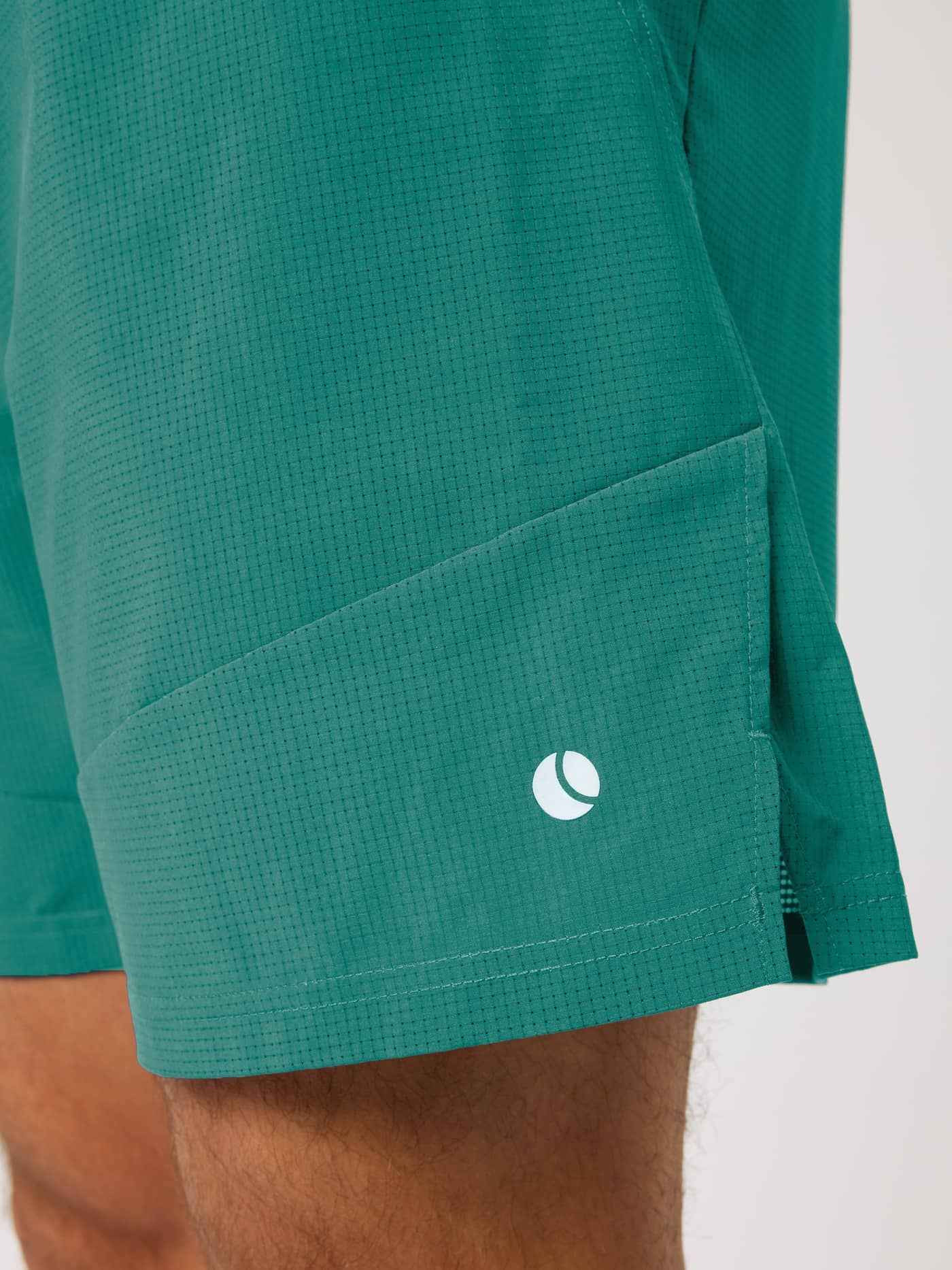 Close-up of Ace Pro Shorts 7 Inch in Mallard Green (Green) for tennis, with perforated weave and white tennis ball logo. - Image 3