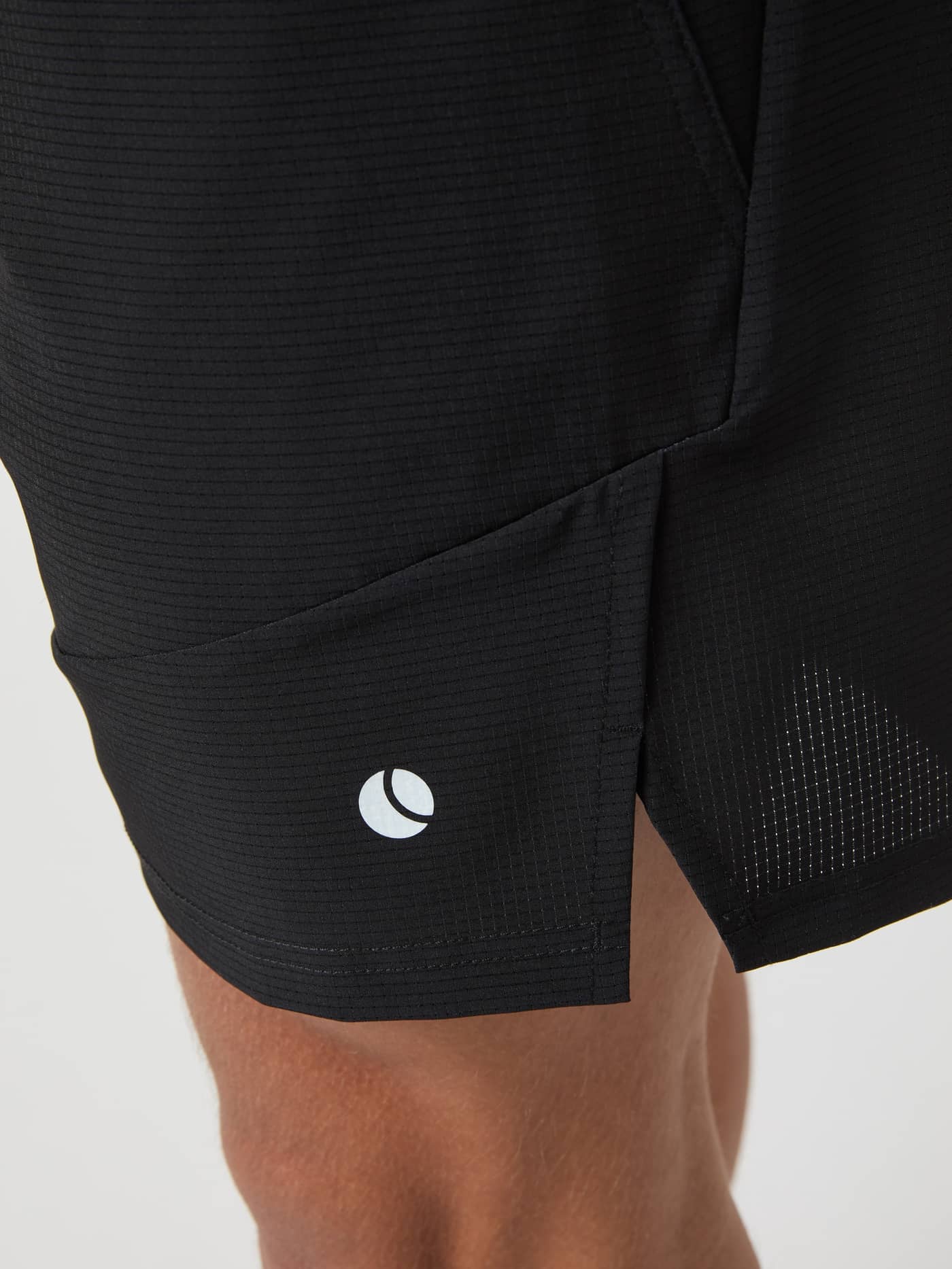 Close-up of the Ace Pro Shorts 7 Inch in Black Beauty (Black), highlighting the white tennis logo and side slit. - Image 4