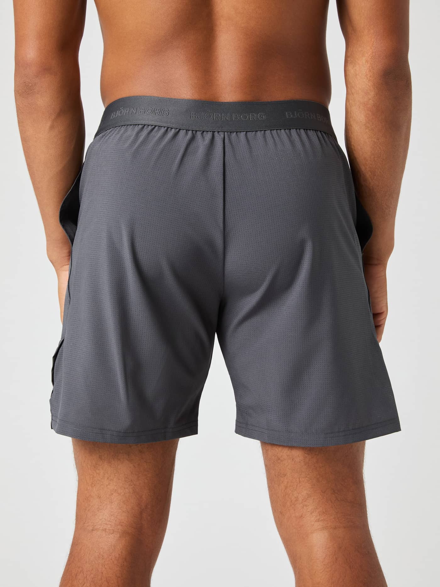 Back view of a model wearing Björn Borg Ace Pro Shorts 7 Inch in Asphalt (Grey) featuring a branded waistband for tennis. - Image 2