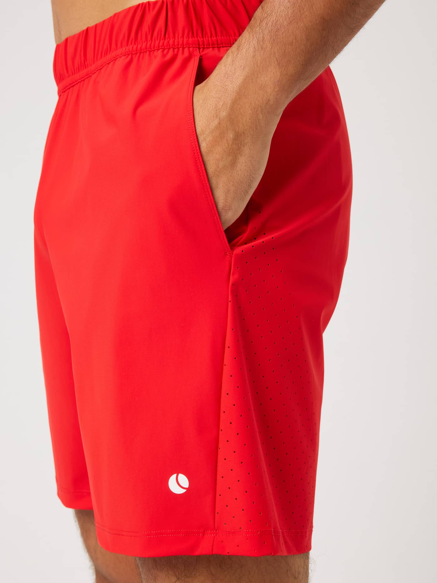 Zijaanzicht van de Ace Sports Shorts 8 Inch in Flame Scarlet (Rood) met geperforeerde panelen en een wit tennisballenlogo. - Image 4
