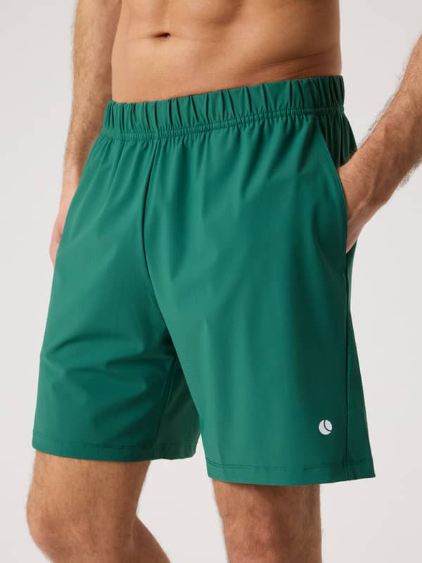 Close-up front view of a man wearing the Ace Sports Shorts 8 Inch in Posy Green (Green) for tennis performance.
