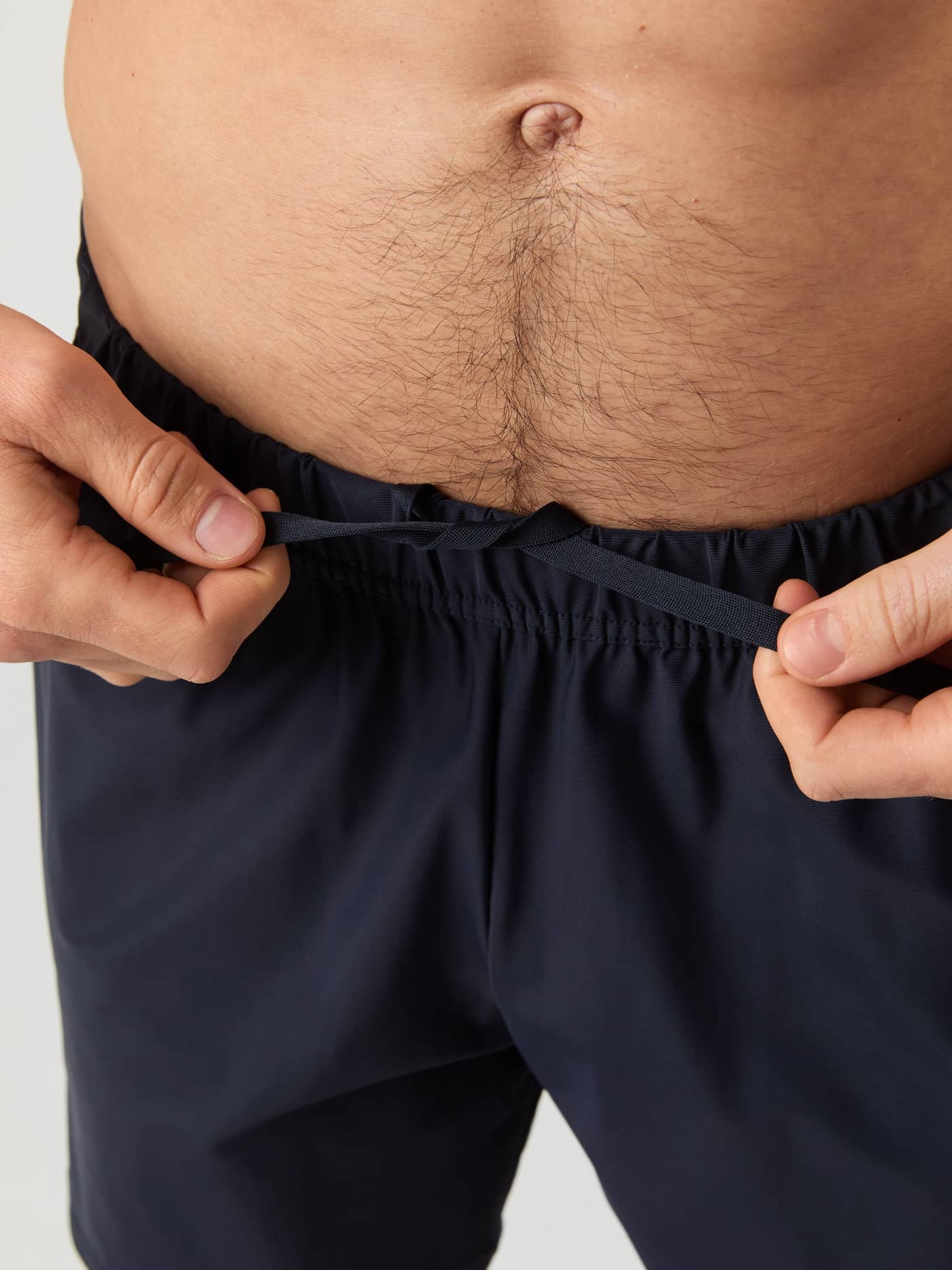 Close-up of a model tying the drawstring at the waist of the navy Björn Borg Ace Sports Shorts. - Image 2