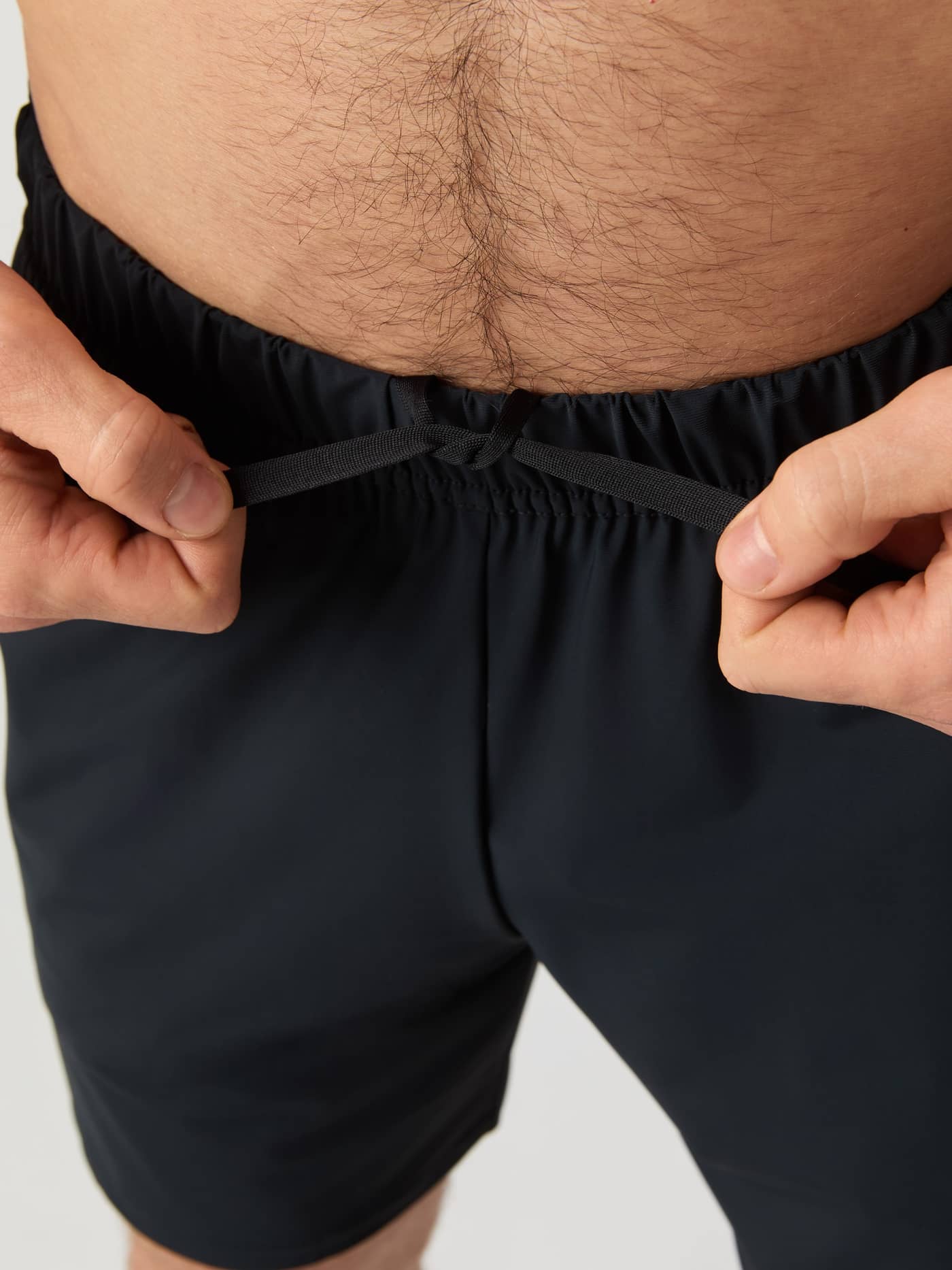 Gros plan d'un homme nouant le cordon de serrage du Ace Sports Shorts 8 inch en Black Beauty (Noir) pour le tennis. - Image 4
