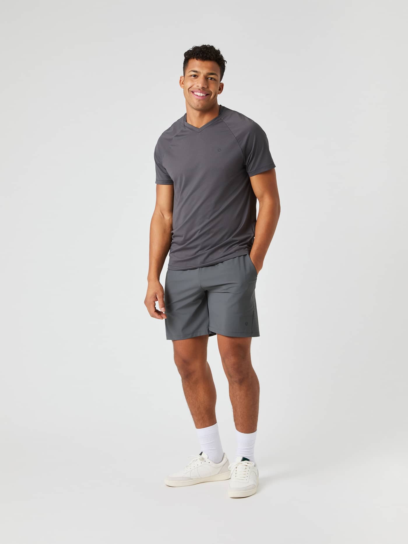 Full body view of a man wearing the Björn Borg Ace Sports 8" Shorts in Asphalt grey with a matching grey v-neck t-shirt. - Image 3