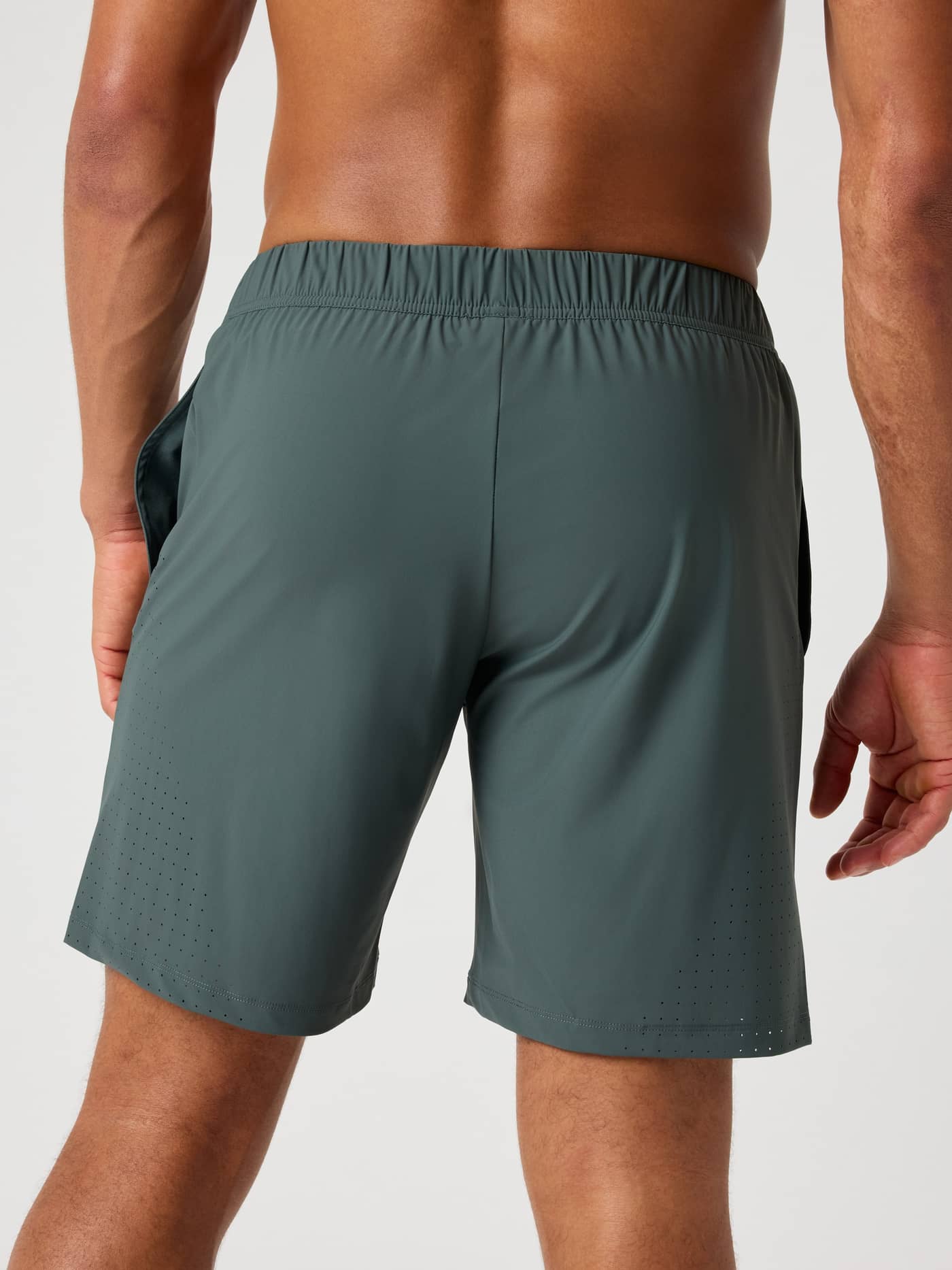 Back view of a man in the Björn Borg Ace Sports Shorts 8 Inch in Urban Chic (Green), functional perforated tennis shorts. - Image 2