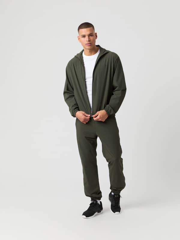 Ace Track Pants i Peat (Grønn) i elastisk polyamid for tennis og trening på en mann, sett forfra.