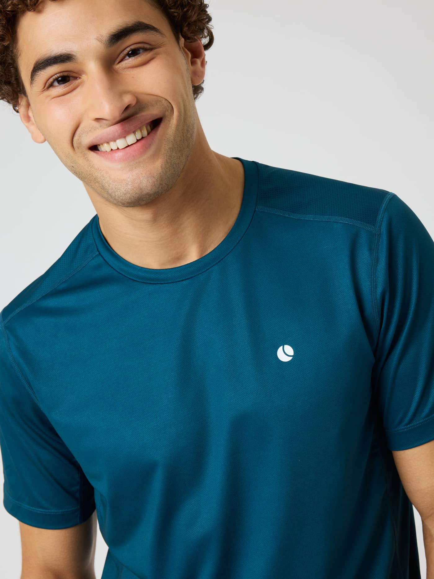 Gros plan d'un homme portant le Ace Mesh Panel T-Shirt en Reflecting Pond (Bleu) pour le tennis avec un logo blanc. - Image 5