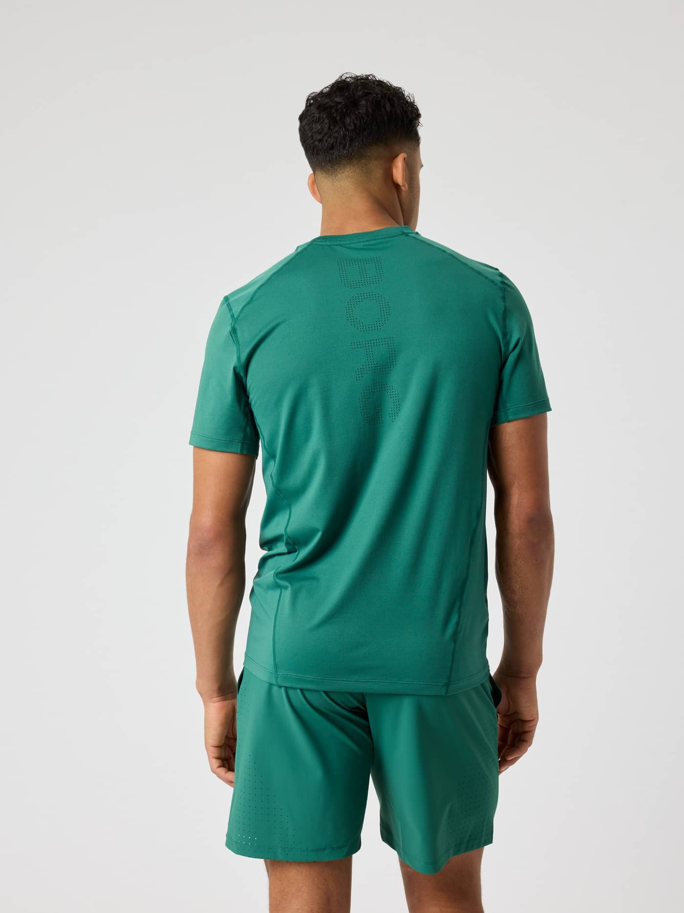 Back view of a man wearing the Björn Borg Ace Mesh Panel T-Shirt in Posy Green (Green) with a perforated logo for tennis. - Image 2