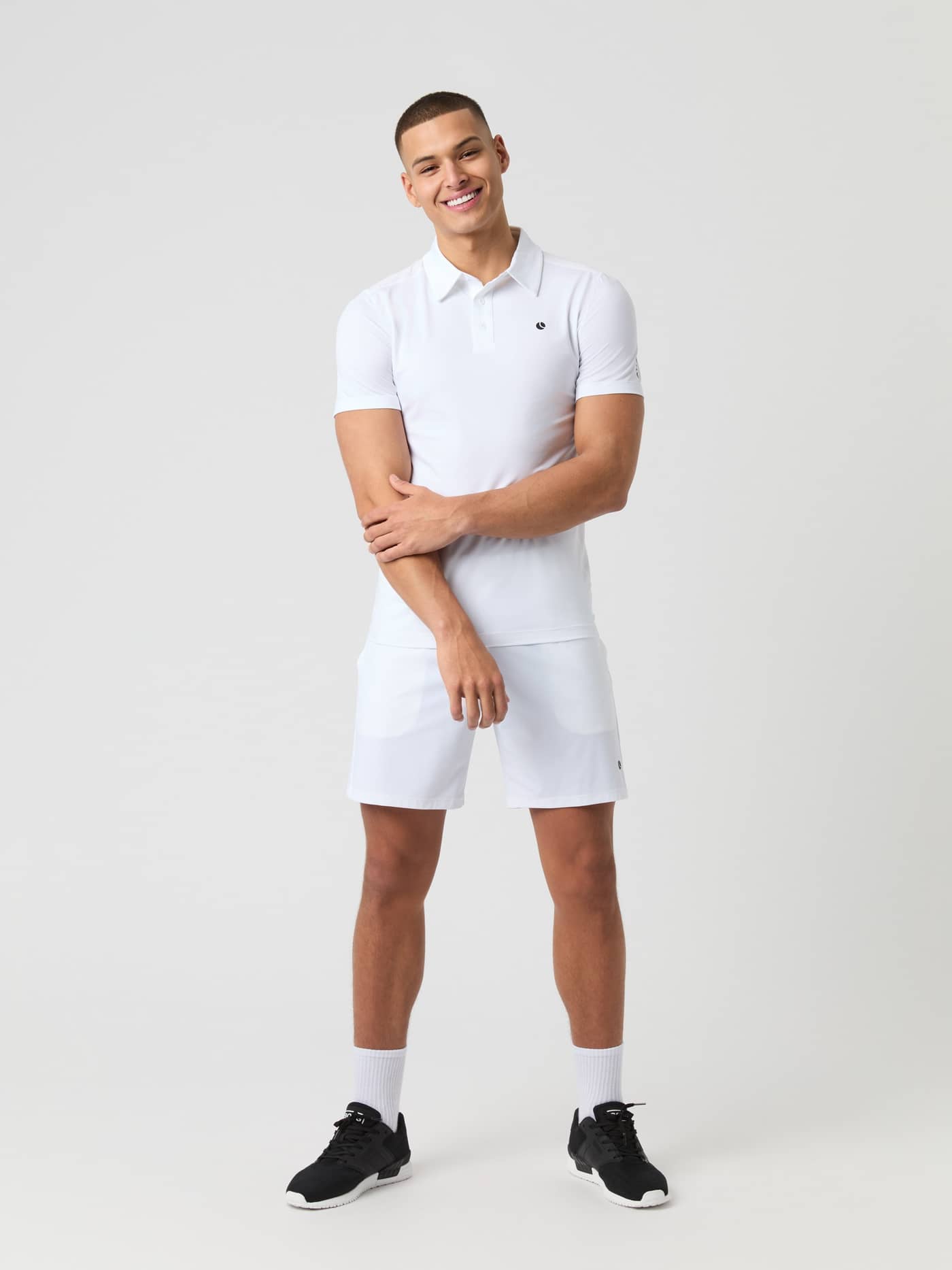 Full-body front view of a man in the Brilliant White (White) Björn Borg Ace Mesh Panel Polo Shirt with a black tennis logo. - Image 3