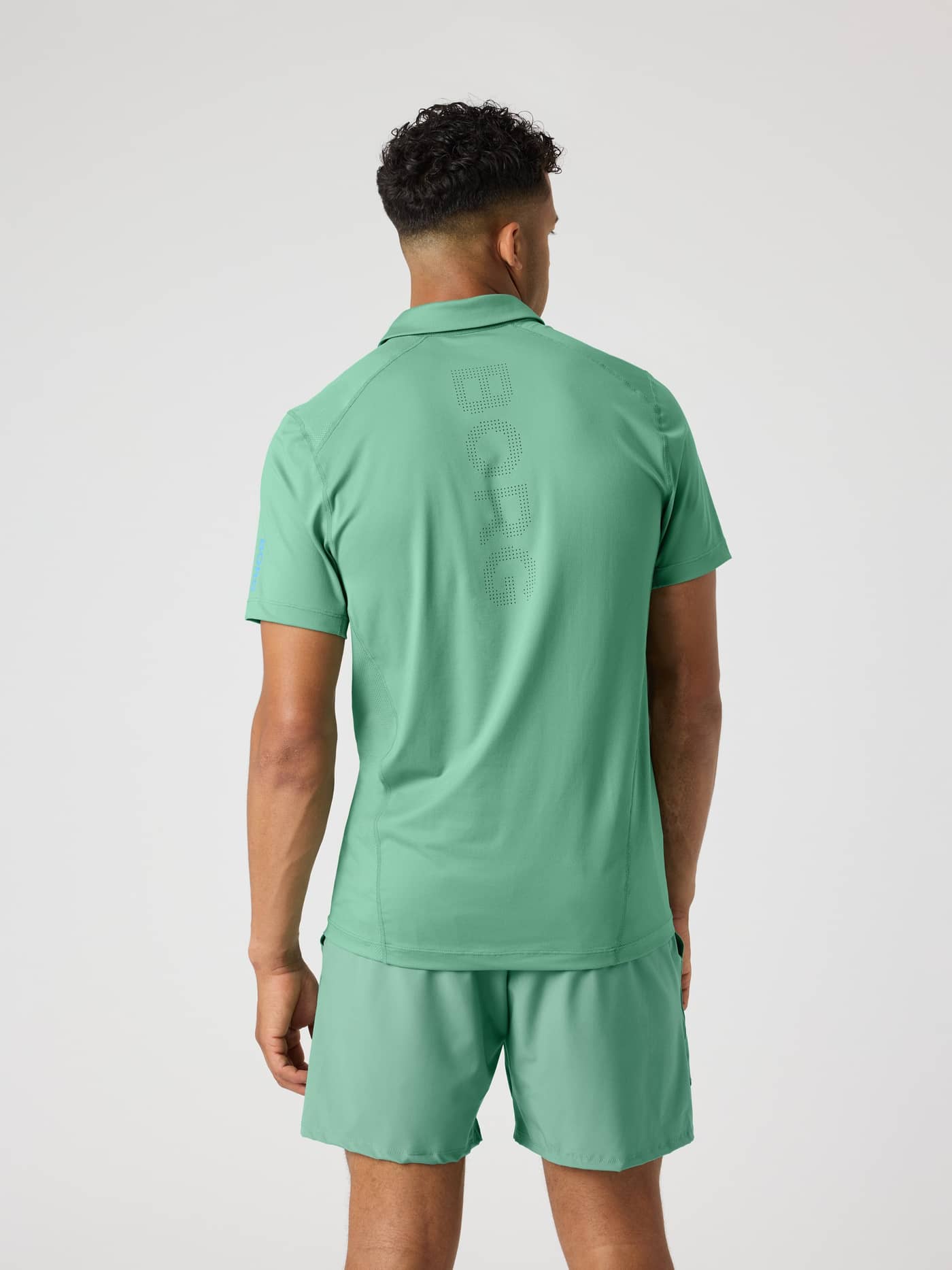 Back view of a man in the Malachite Green (Green) Ace Mesh Panel Polo Shirt with a perforated Borg logo for tennis. - Image 2