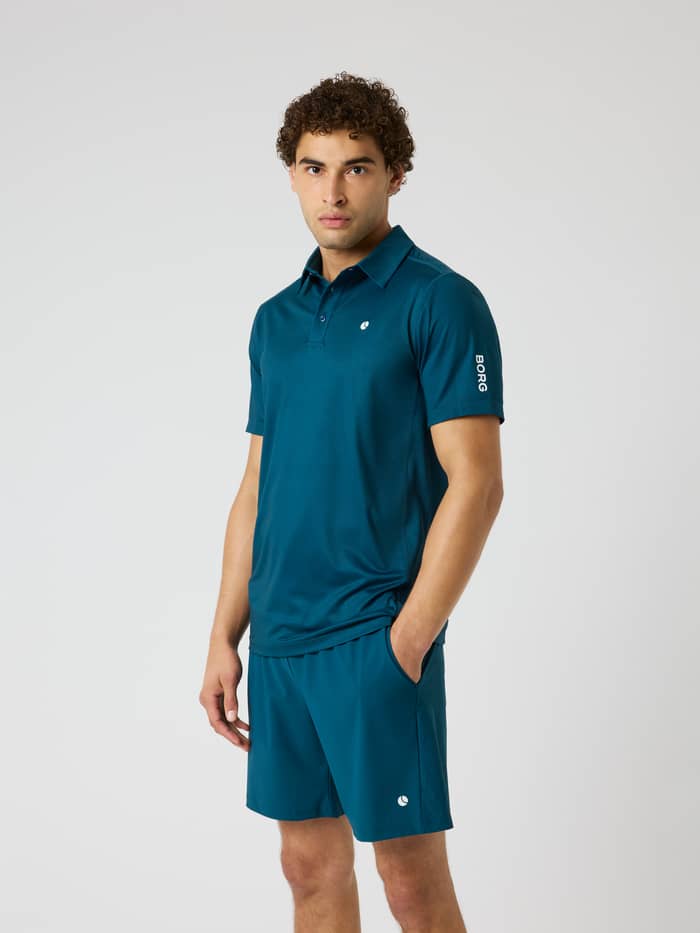 Front view of a model in the Ace Mesh Panel Polo Shirt in Reflecting Pond (Green) for performance tennis and padel.