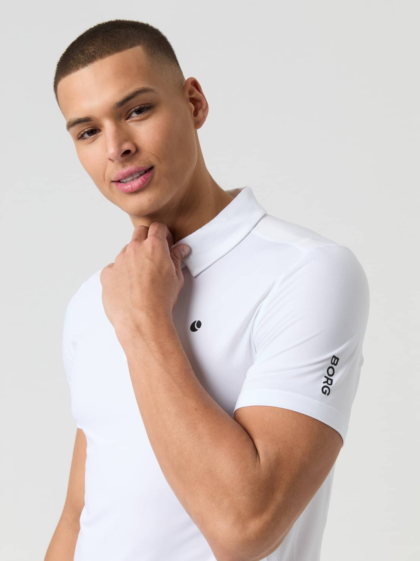 Front view of a model in the Björn Borg Ace Mesh Panel Polo Shirt in Brilliant White (White) with black logos for tennis. - Image 5