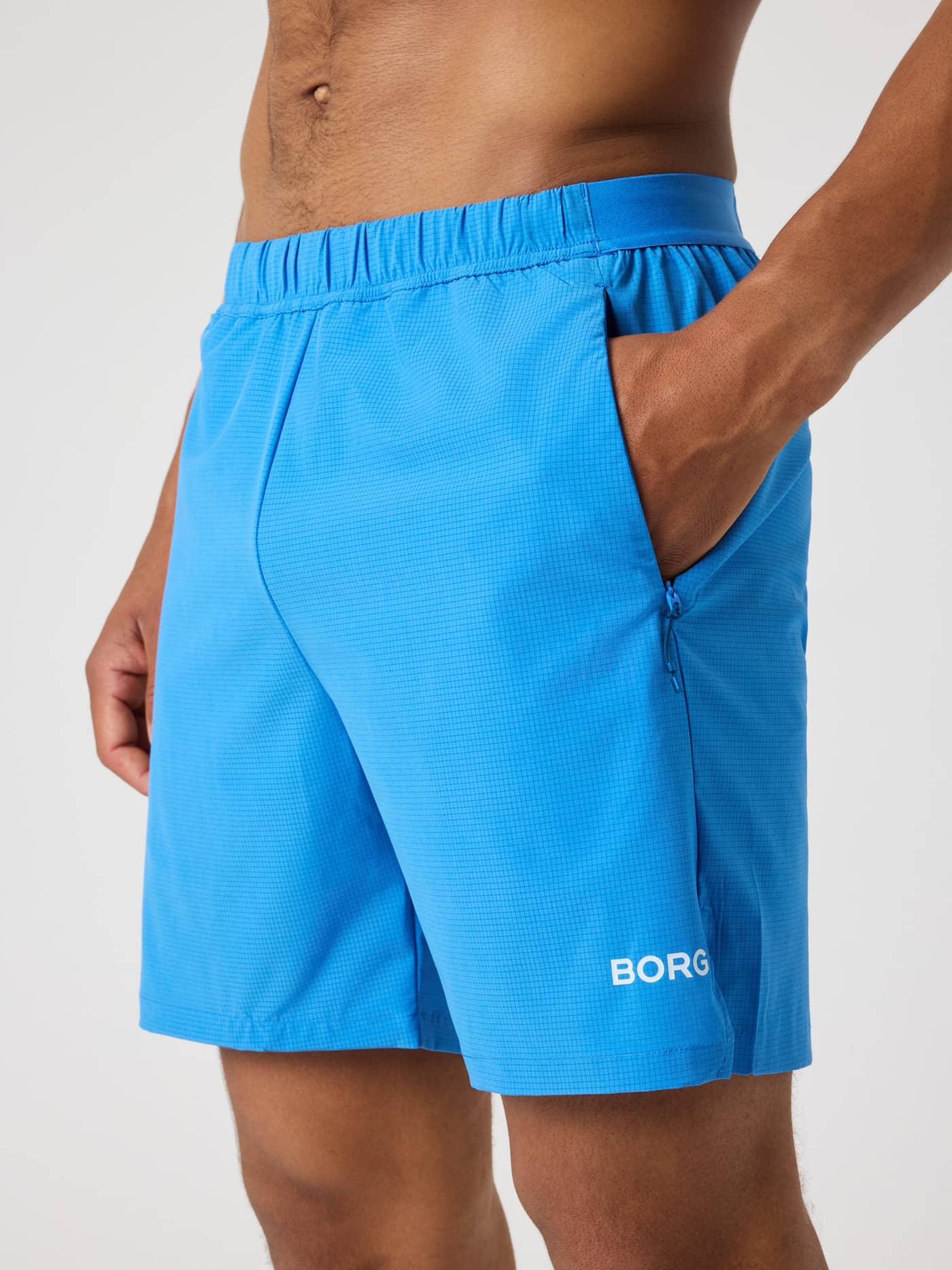 Borg Zip Shorts 7 Inch i Palace Blue (Blå) set fra siden med et hvidt logo og lynlåslommer til træning. - Image 4