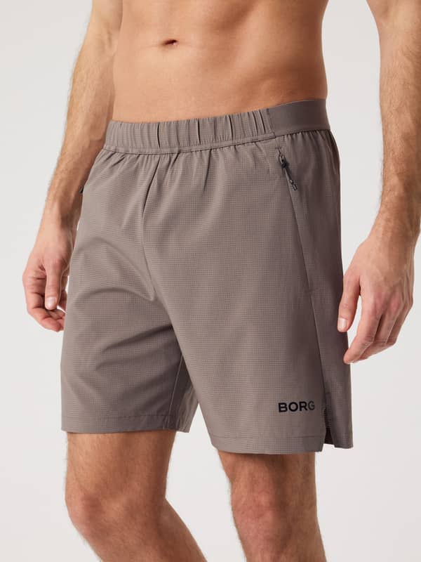 Vooraanzicht van een man in de Borg Zip Shorts 7 Inch in Falcon (Bruin) met zwart logo en zijsplitjes voor training.