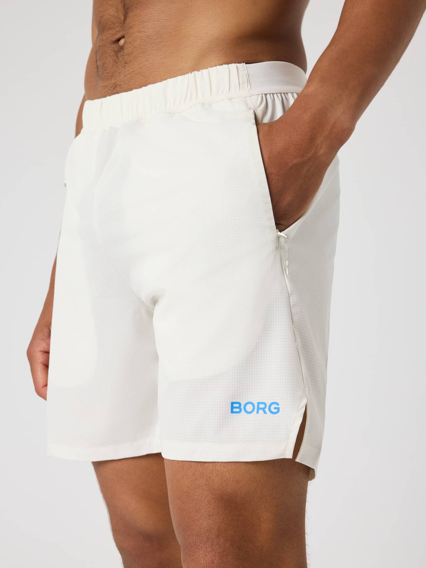 Borg Zip Shorts 7 Inch i Tofu (Hvid) set fra siden med blåt logo og teknisk jacquard-stof til træning. - Image 4