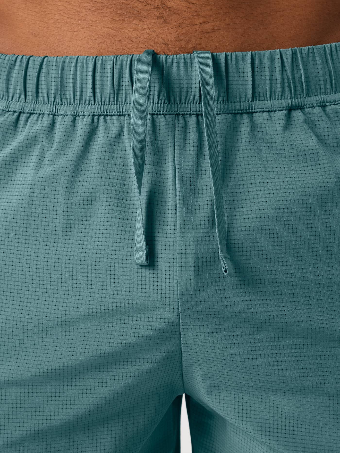 Close-up of the Balsam Green (Green) Borg Zip Shorts 7 Inch, showing the drawstring and technical perforated training fabric. - Image 6