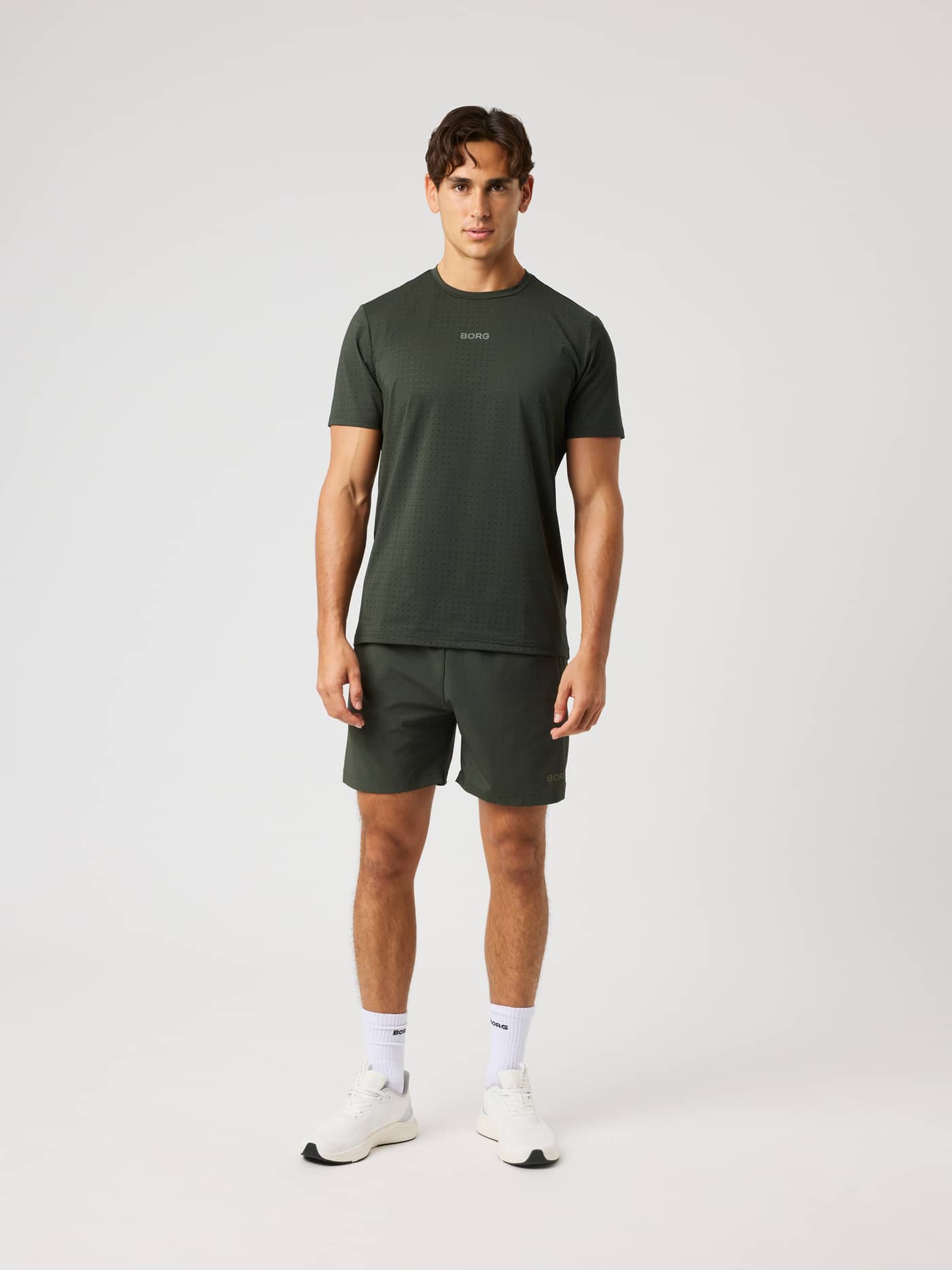 Full-body front view of a man wearing Borg Zip Shorts 7 Inch in Rosin (Green) for training and gym sessions. - Image 3