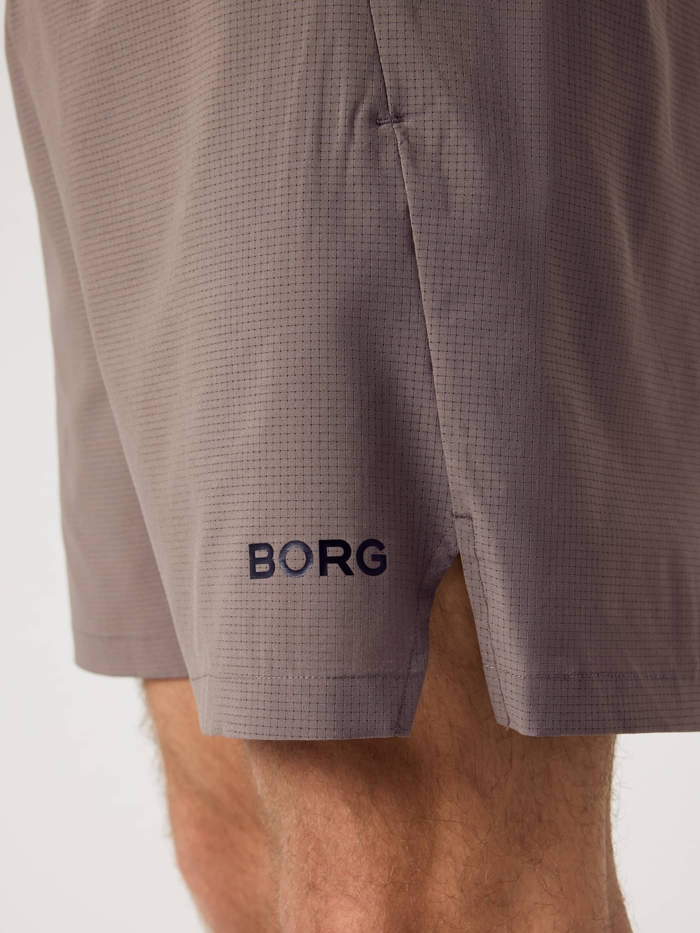 Close-up van de Borg Zip Shorts 7 Inch in Falcon (Bruin) met technische trainingsstof en een zijsplit. - Image 4