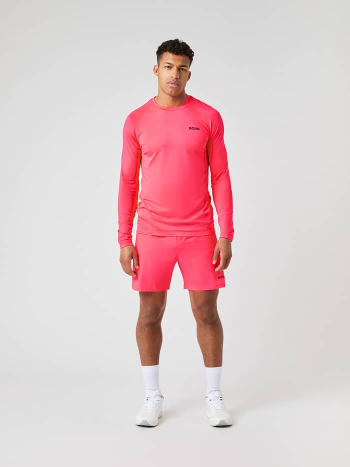 Front view of a model wearing the Björn Borg Borg Zip 7" Shorts in bright pink, paired with a matching long-sleeved top.