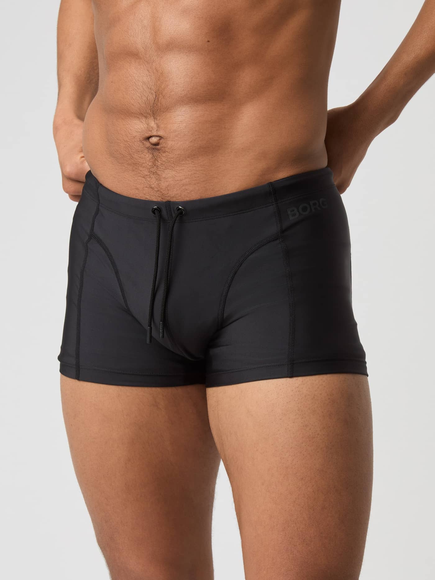 Front view of a man wearing the slim-fit Borg Swim Trunks in Black Beauty (Black) for training, featuring a black logo. - Image 2