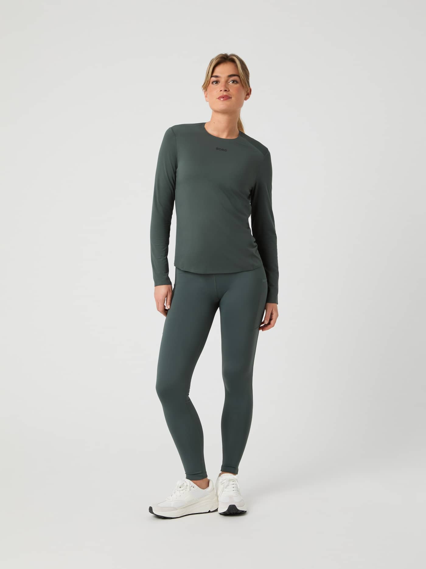 Full-body front view of a woman wearing the Urban Chic (Green) Borg Running Feather Long Sleeve T-Shirt with black logo. - Image 3
