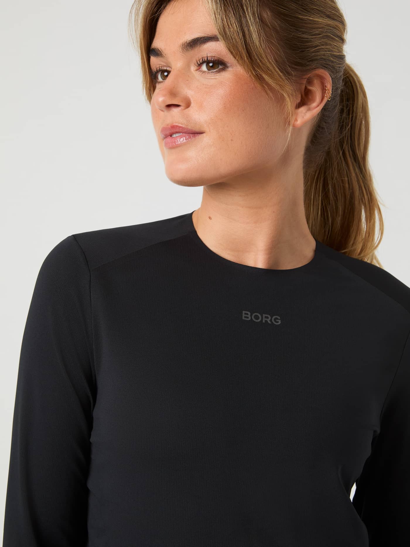 Close-up of a woman wearing the Black Beauty (Black) Borg Running Feather Long Sleeve T-Shirt with a grey logo for running. - Image 4