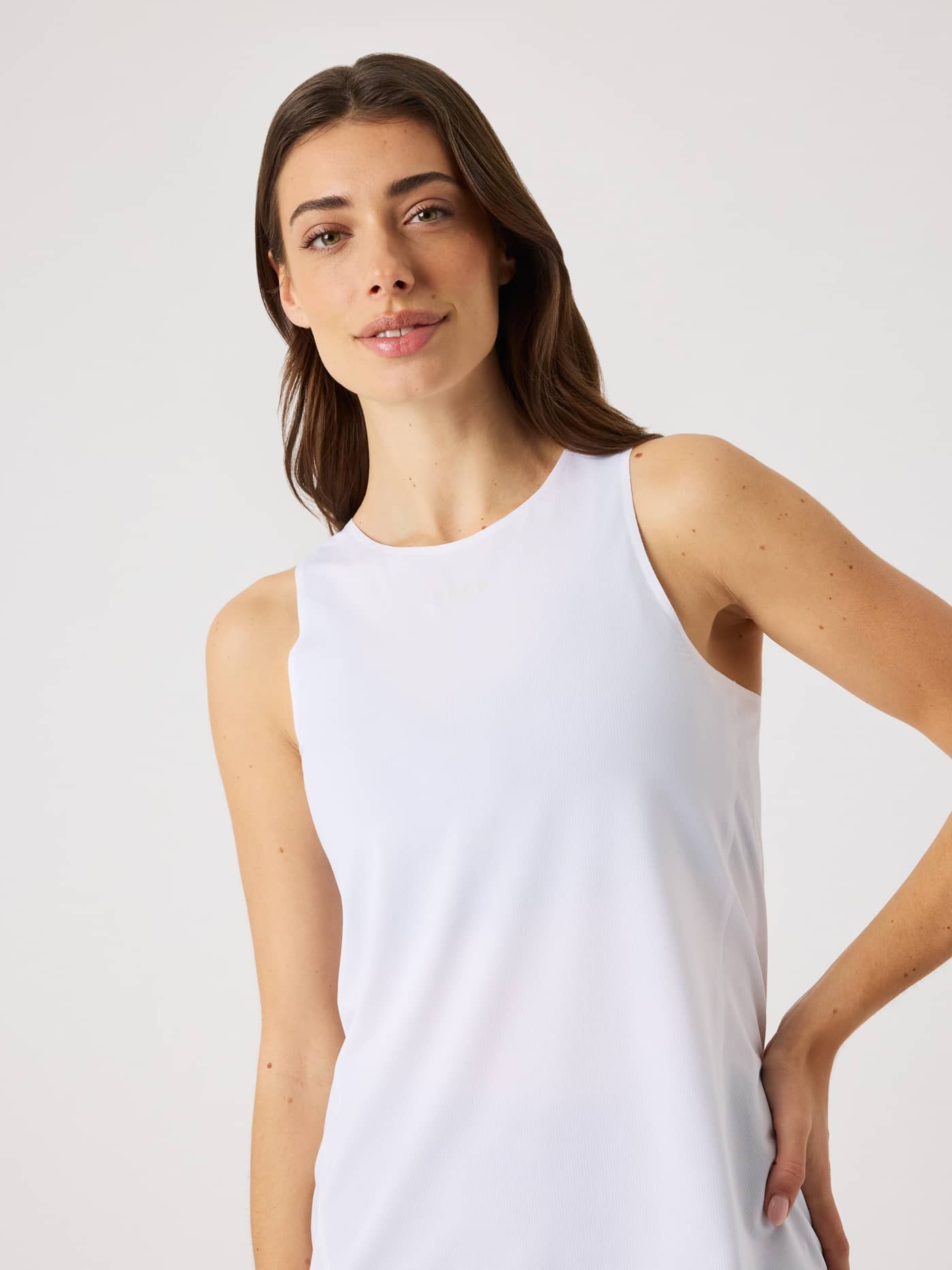 Front view of a woman in the breathable Borg Performance Feather Tank in Brilliant White (White) for running and training. - Image 4