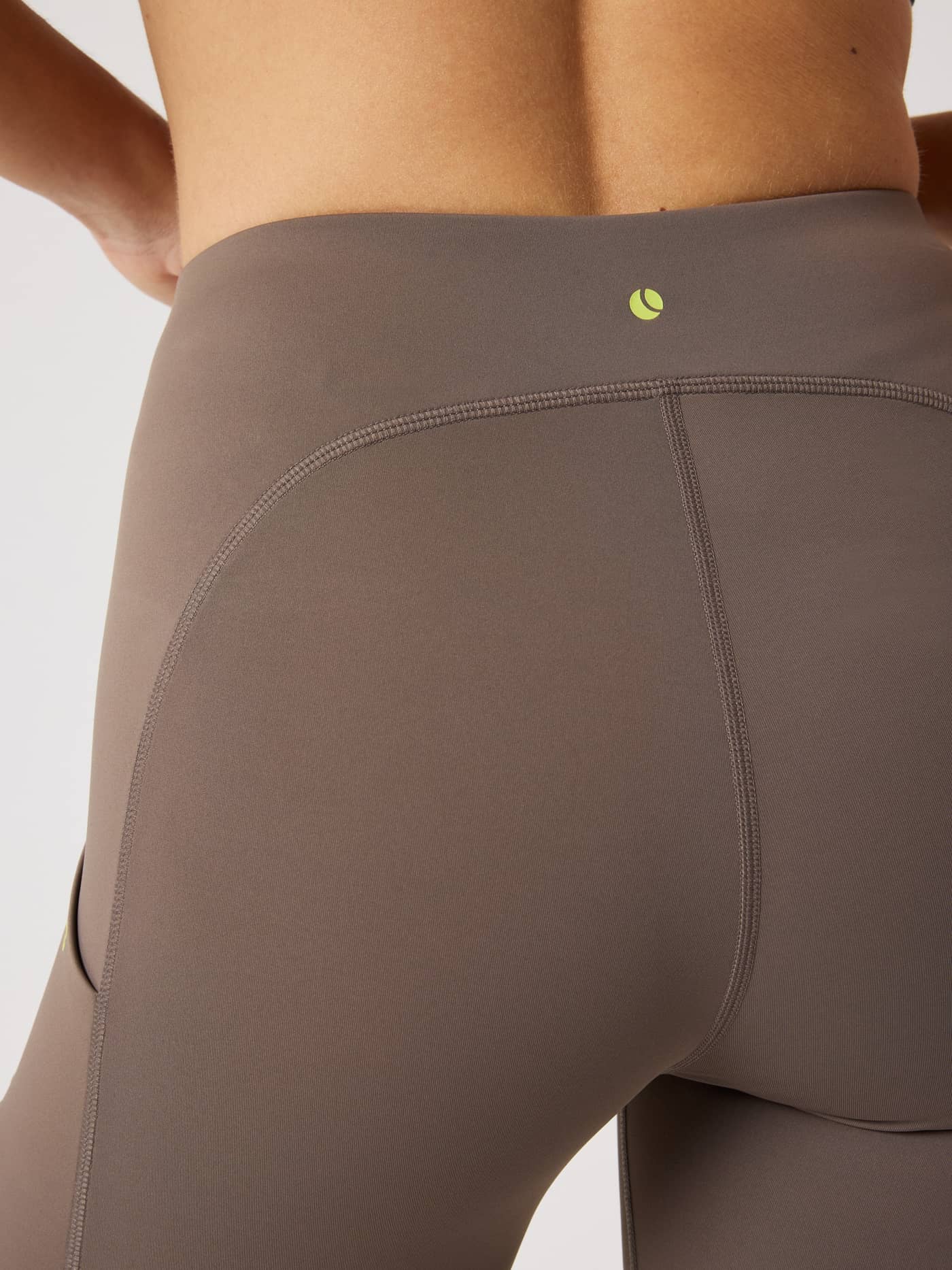 Detailed back view of the slim-fit Borg Performance Short Tights in Falcon (Brown) for running with a lime green logo. - Image 4
