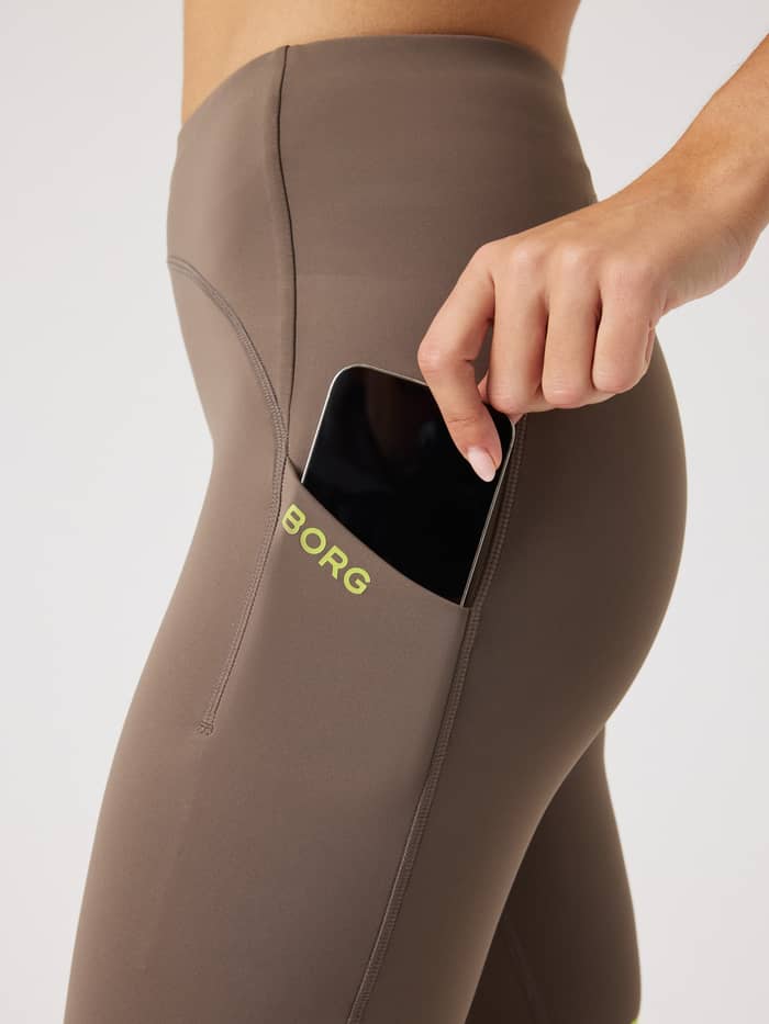 Side phone pocket on the Falcon (Brown) Borg Performance Short Tights for women, featuring a lime logo and sleek running fit. - Image 5