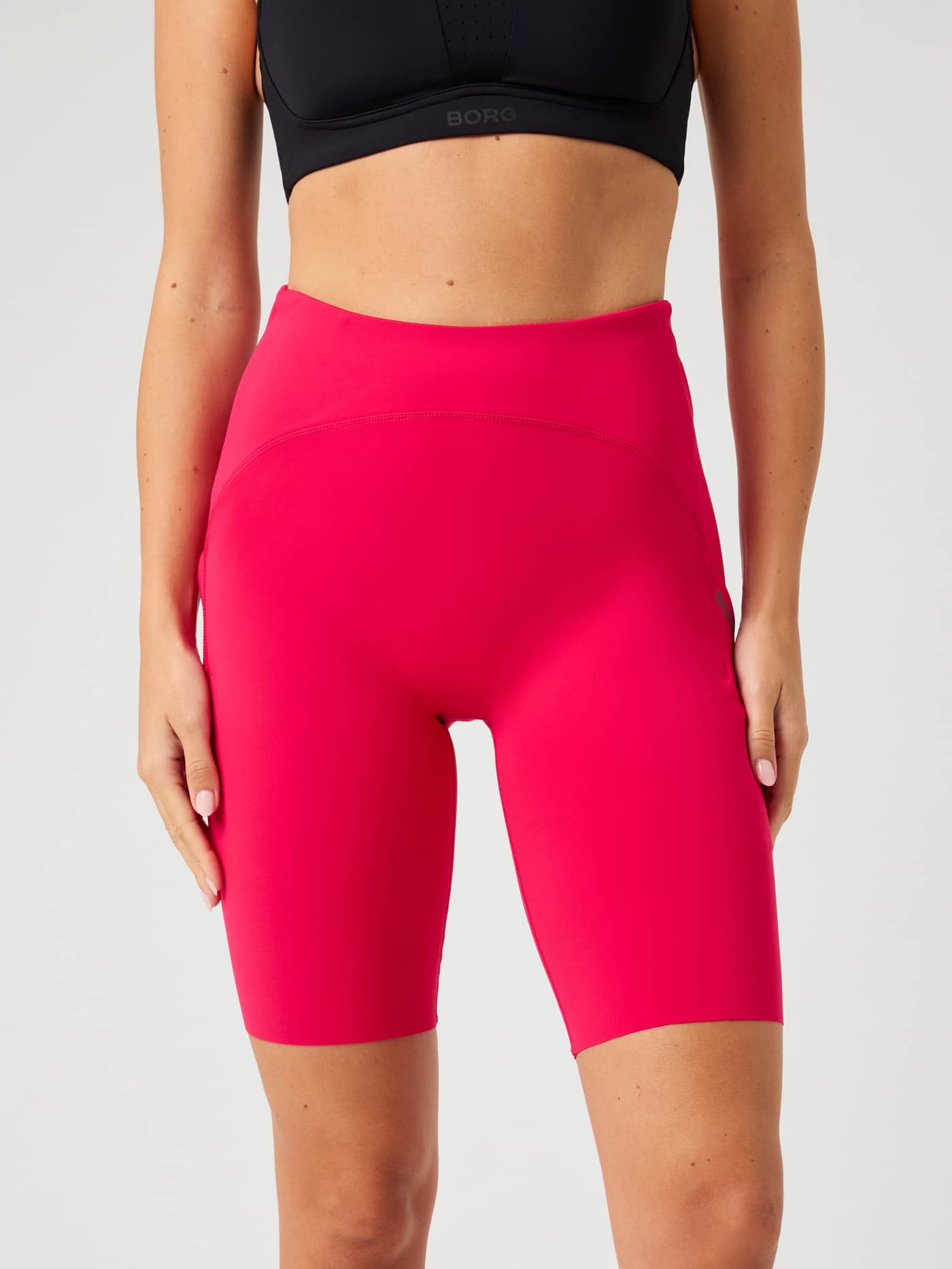 Vista frontal de una modelo con las Borg Running Short Tights en Love Potion (Rosa) de ajuste entallado para running. - Image 2