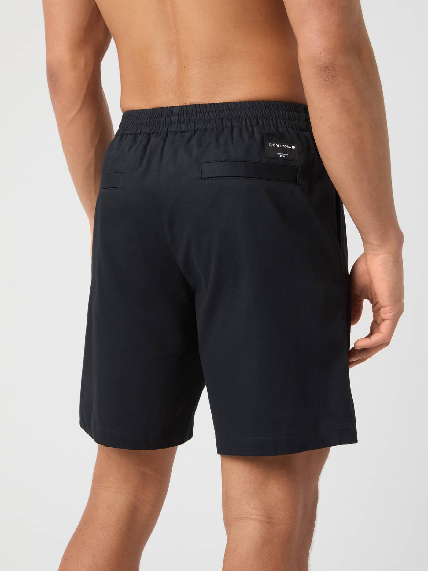 Rückansicht eines Mannes in den lockeren Björn Borg Centre Woven Drawstring Shorts in Black Beauty (Schwarz) mit weißem Logo. - Image 2