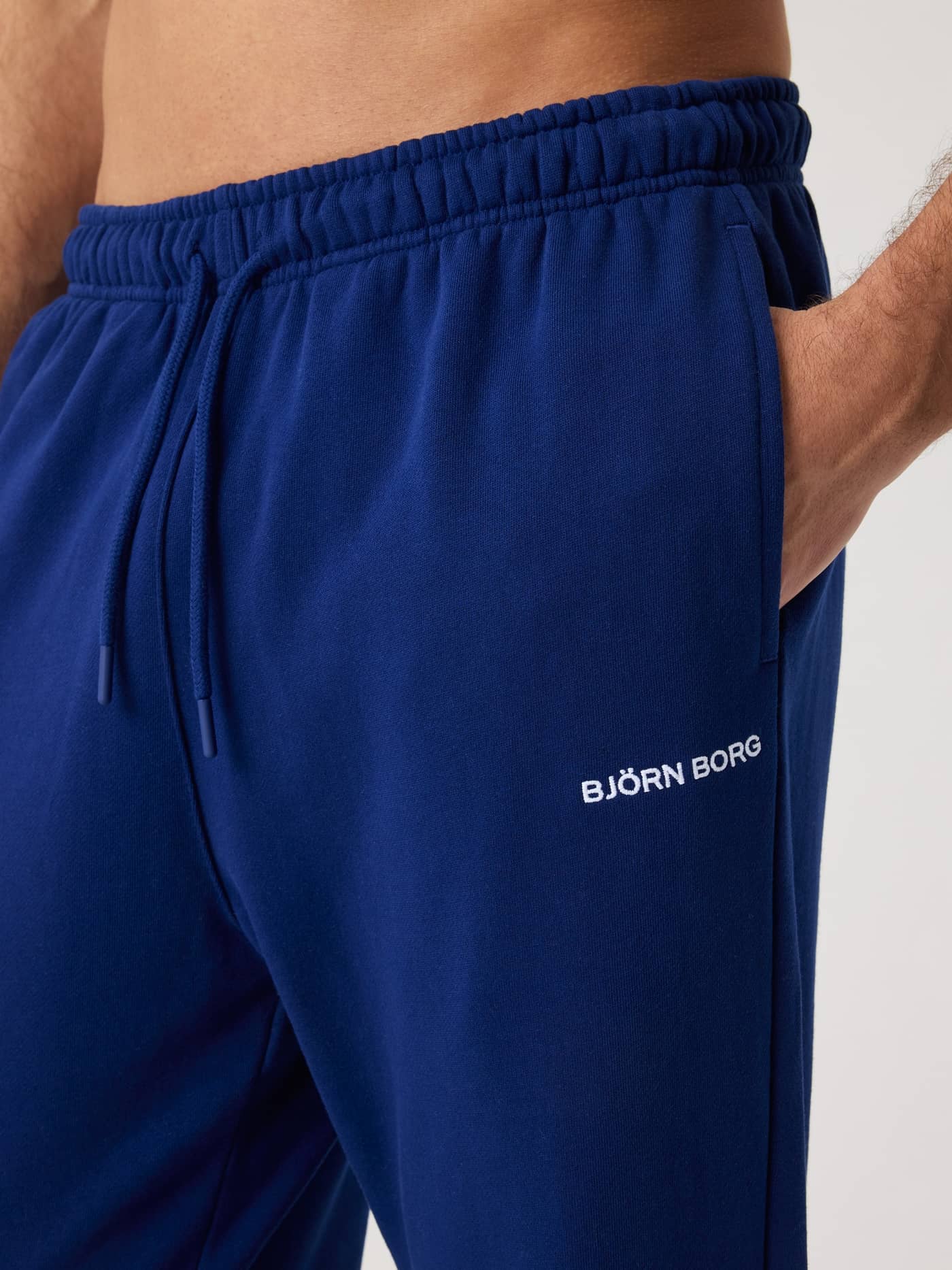 Nahaufnahme der Borg Classic Sweatpants in Blue Depths (Blau) aus Baumwolle mit weißem Logo und funktionalem Kordelzug. - Image 5