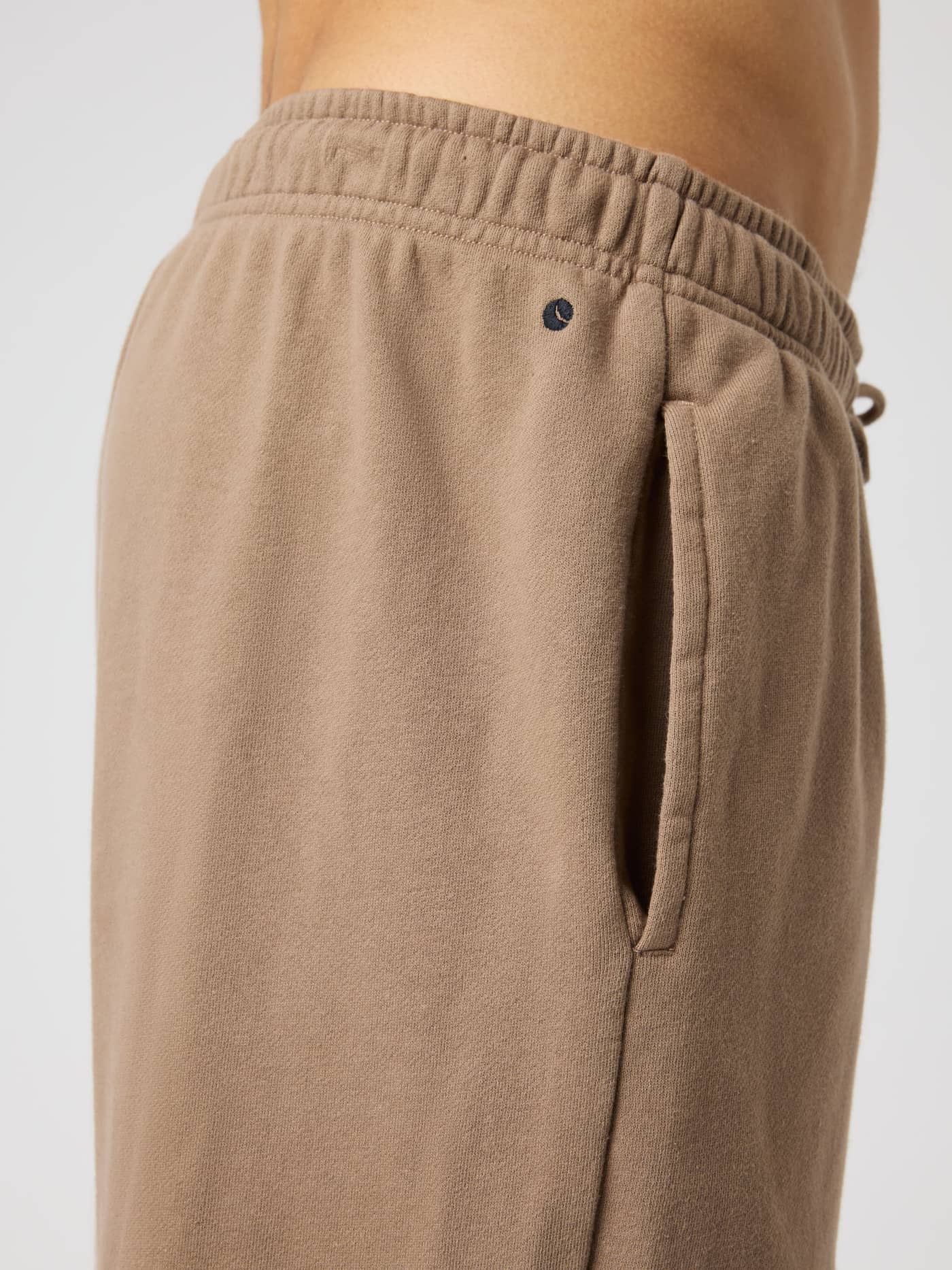 Side view of the Borg Classic Sweatpants in Caribou (Brown) in soft cotton with a side pocket and navy logo detail. - Image 6