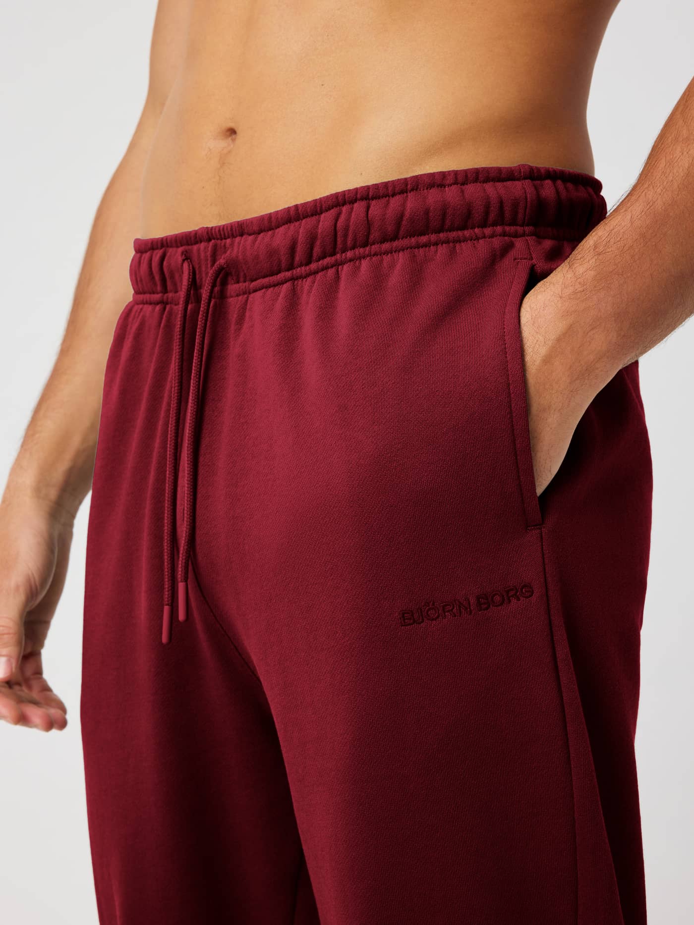 Close-up of the Borg Classic Sweatpants in Cabernet (Red) highlighting the elastic drawstring waist and side pocket. - Image 4