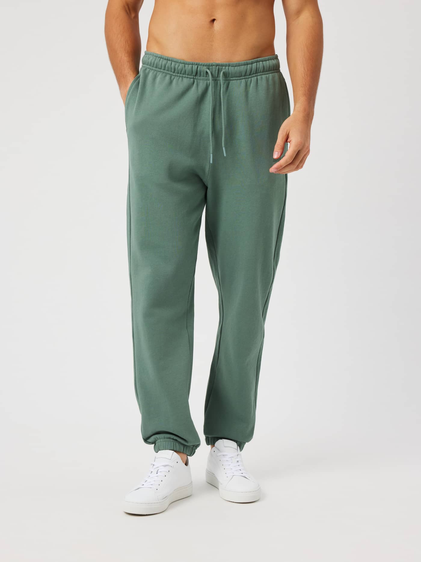 Man wearing Borg Classic Sweatpants in Laurel Wreath (green) featuring a regular fit and an elastic drawstring waist. - Image 1